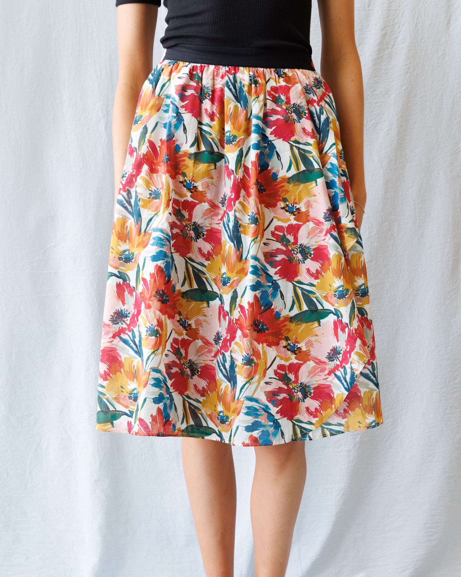 Colorful floral skirt worn by a person on a plain background