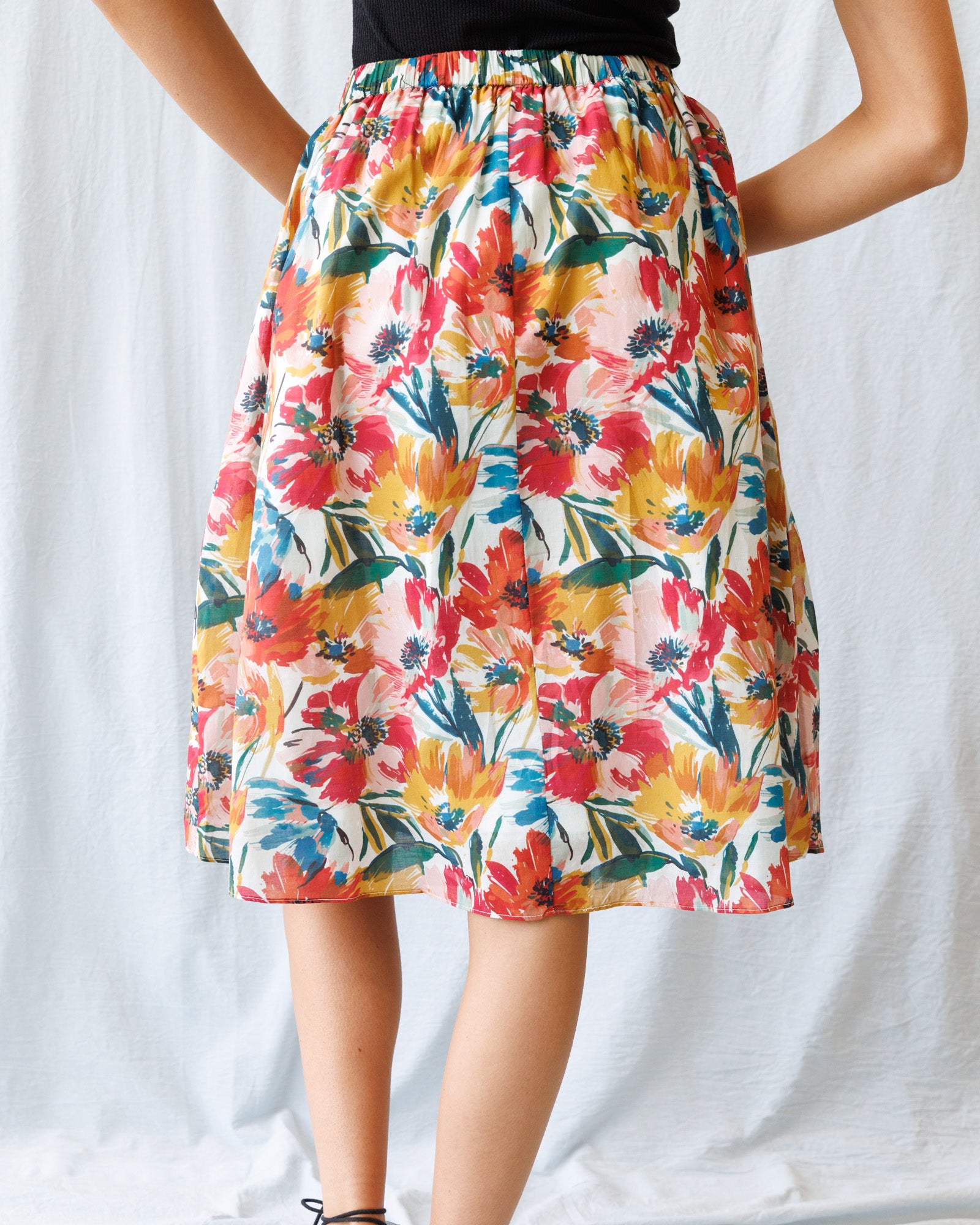 Colorful floral skirt worn by a person on a white background
