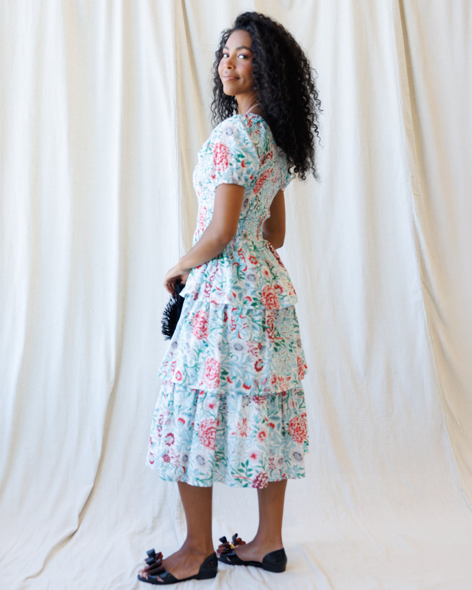 Woman wearing a floral dress against a white curtain background