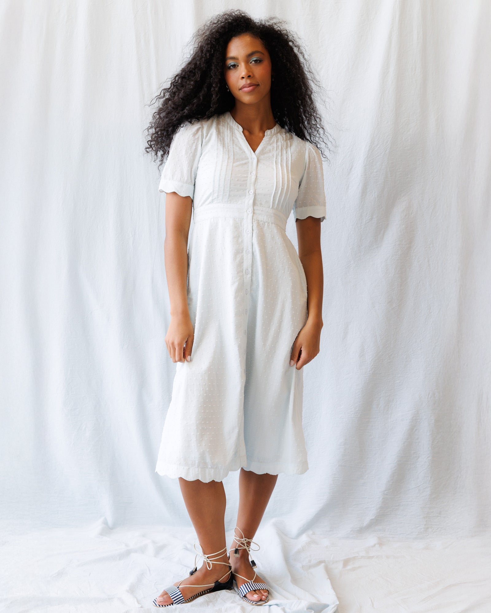 Woman wearing a light blue dress against a plain white background