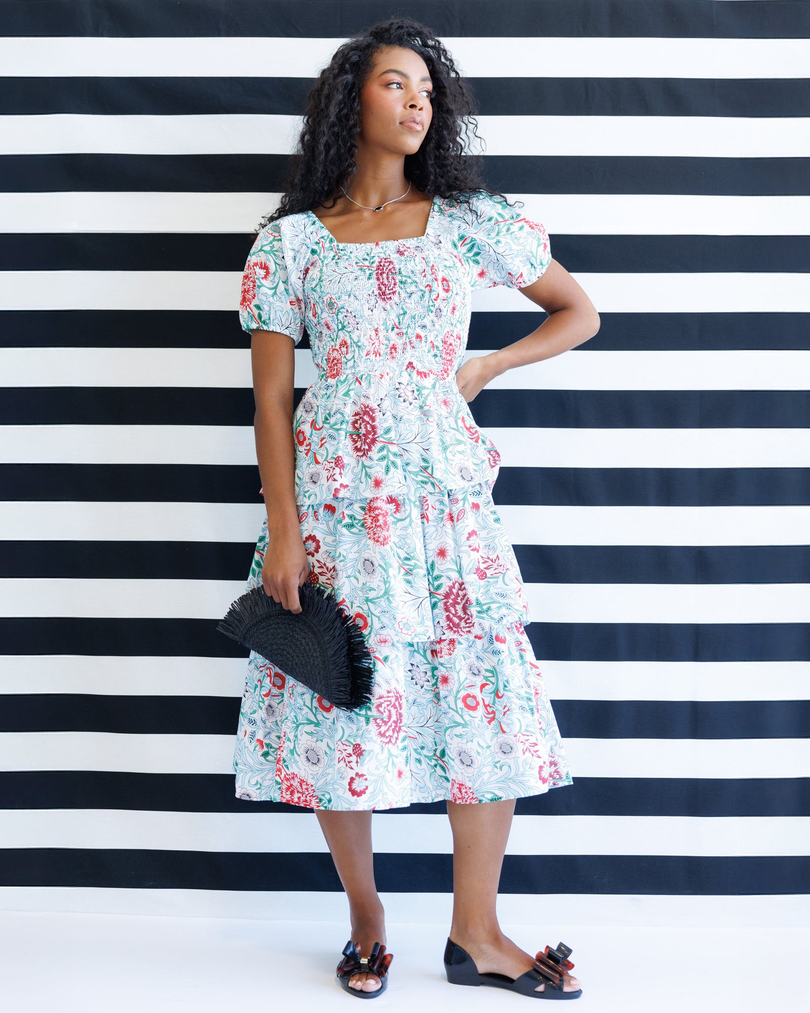 Woman in a floral dress standing against a black and white striped background