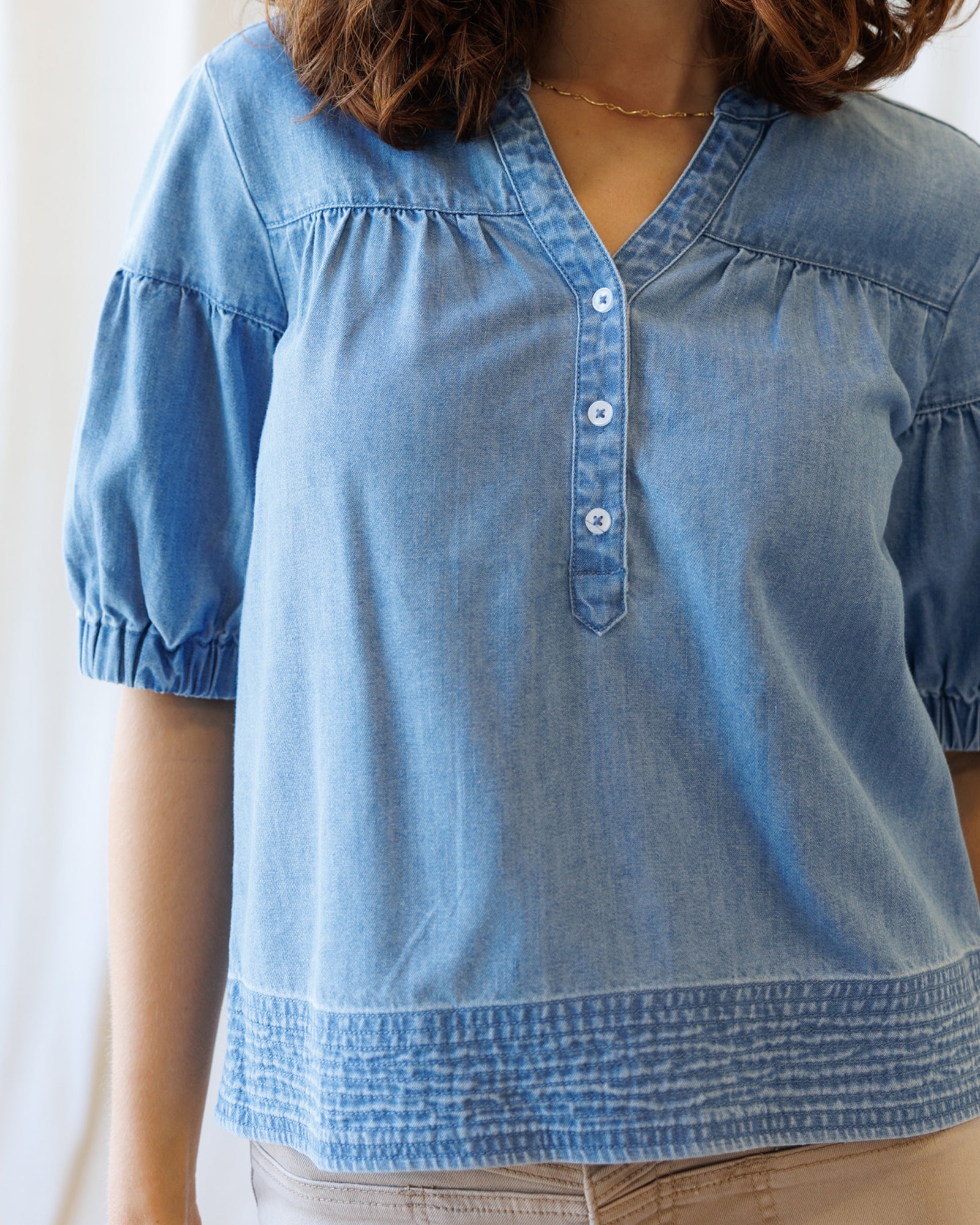 Blue denim blouse worn by a person with a blurred background