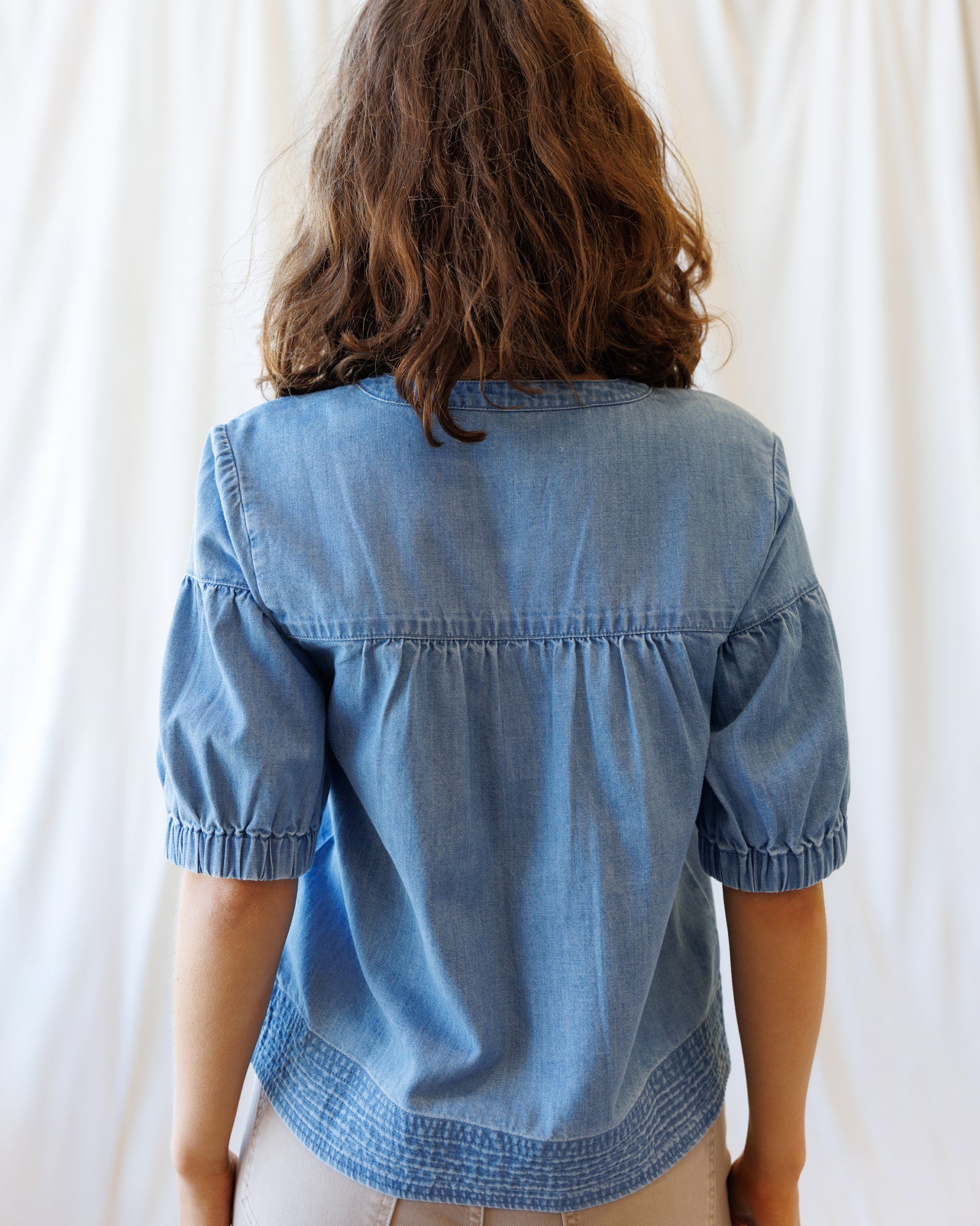 Person wearing a blue denim shirt against a white background