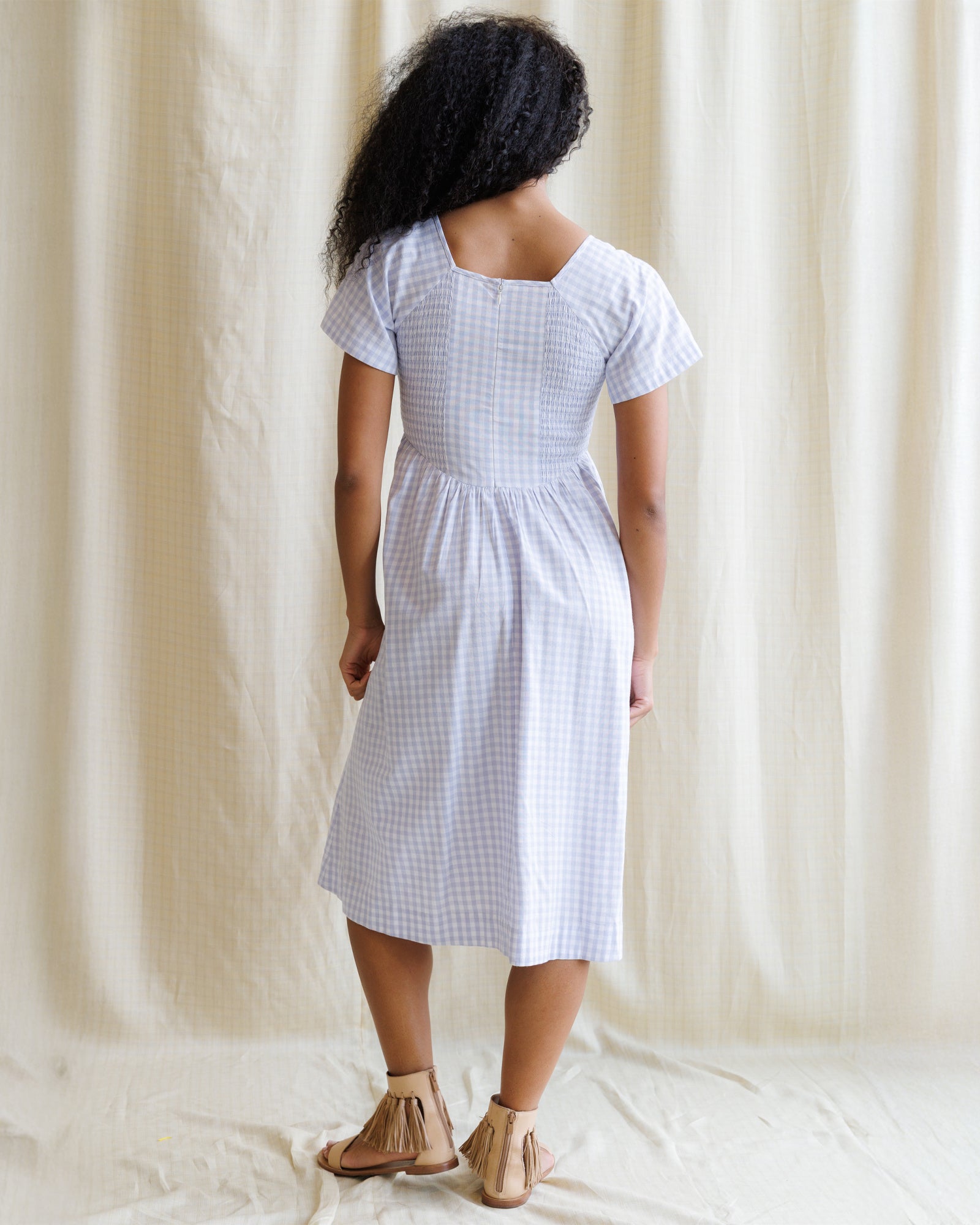 Woman wearing a purple dress with blue checkered pattern against a plain background