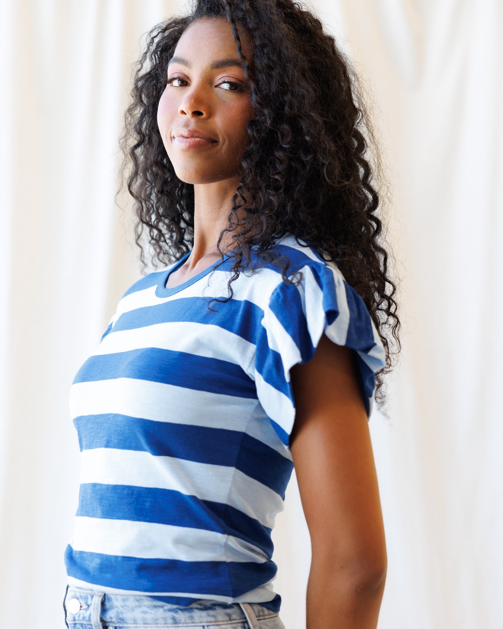 Woman wearing a blue and white striped shirt against a plain background