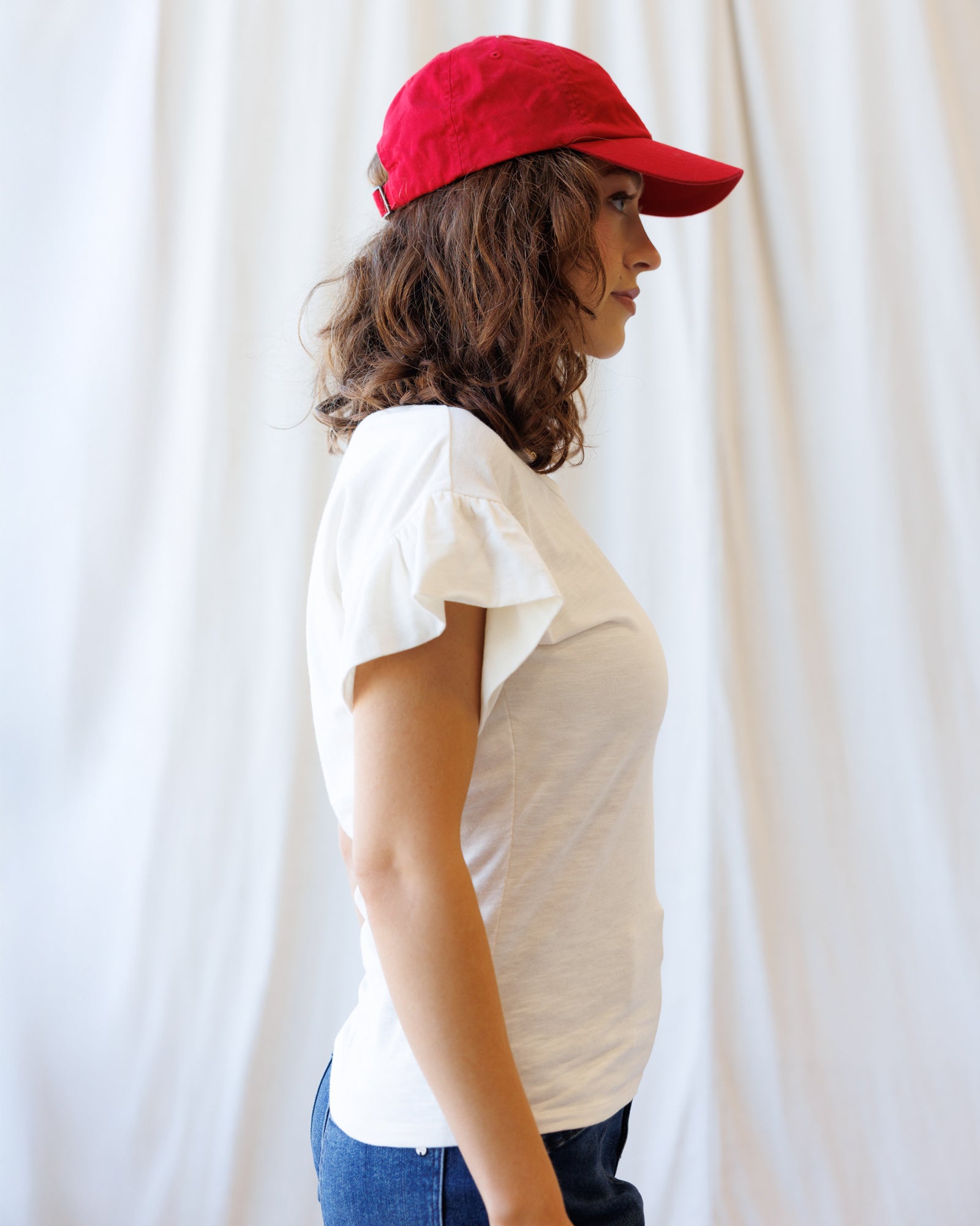 Person wearing a red cap and white shirt against a plain background