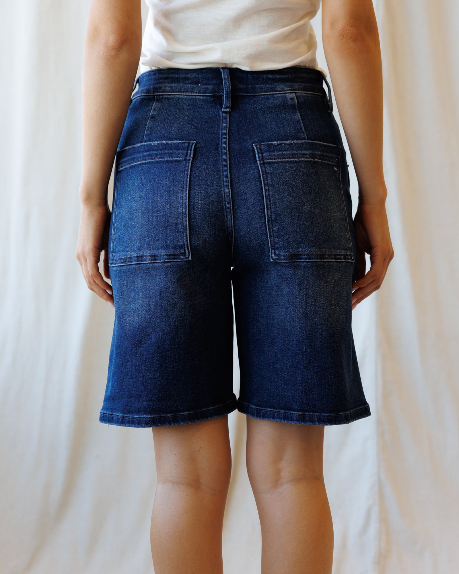 Person wearing blue denim shorts against a plain background