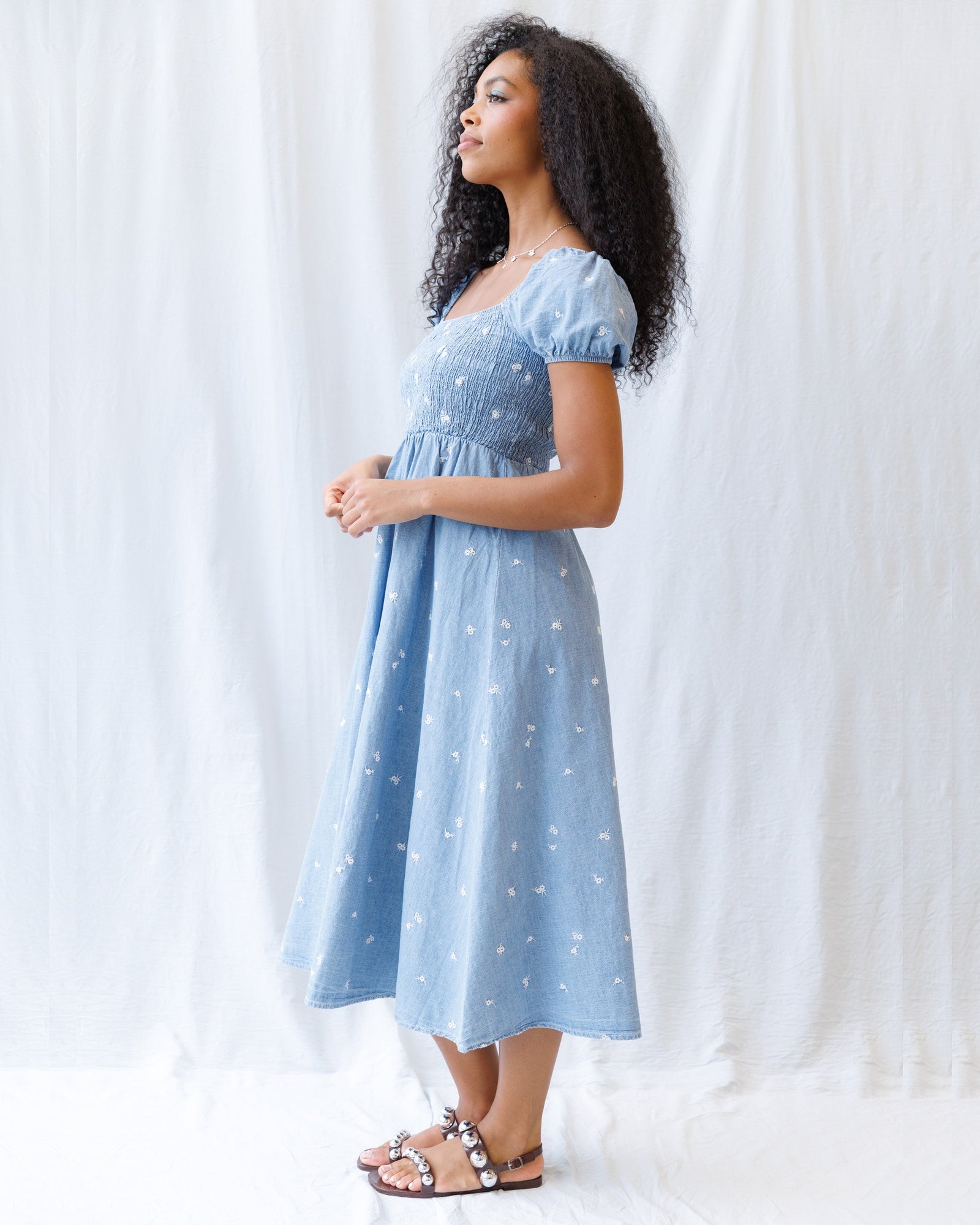 Woman wearing a light blue dress with white polka dots against a white background