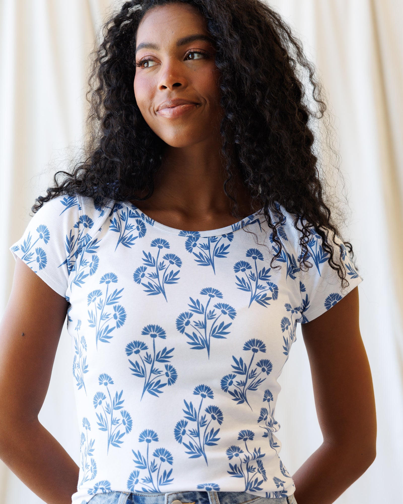 Woman wearing a white t-shirt with blue floral pattern against a plain background
