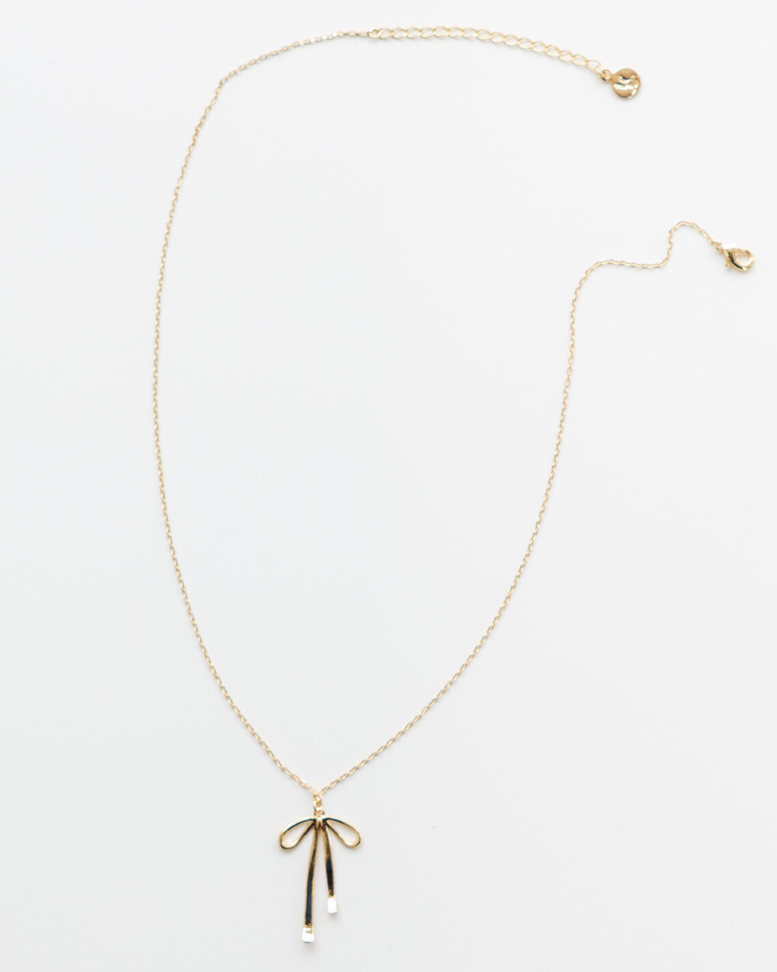 Gold necklace with a bow pendant on a white background