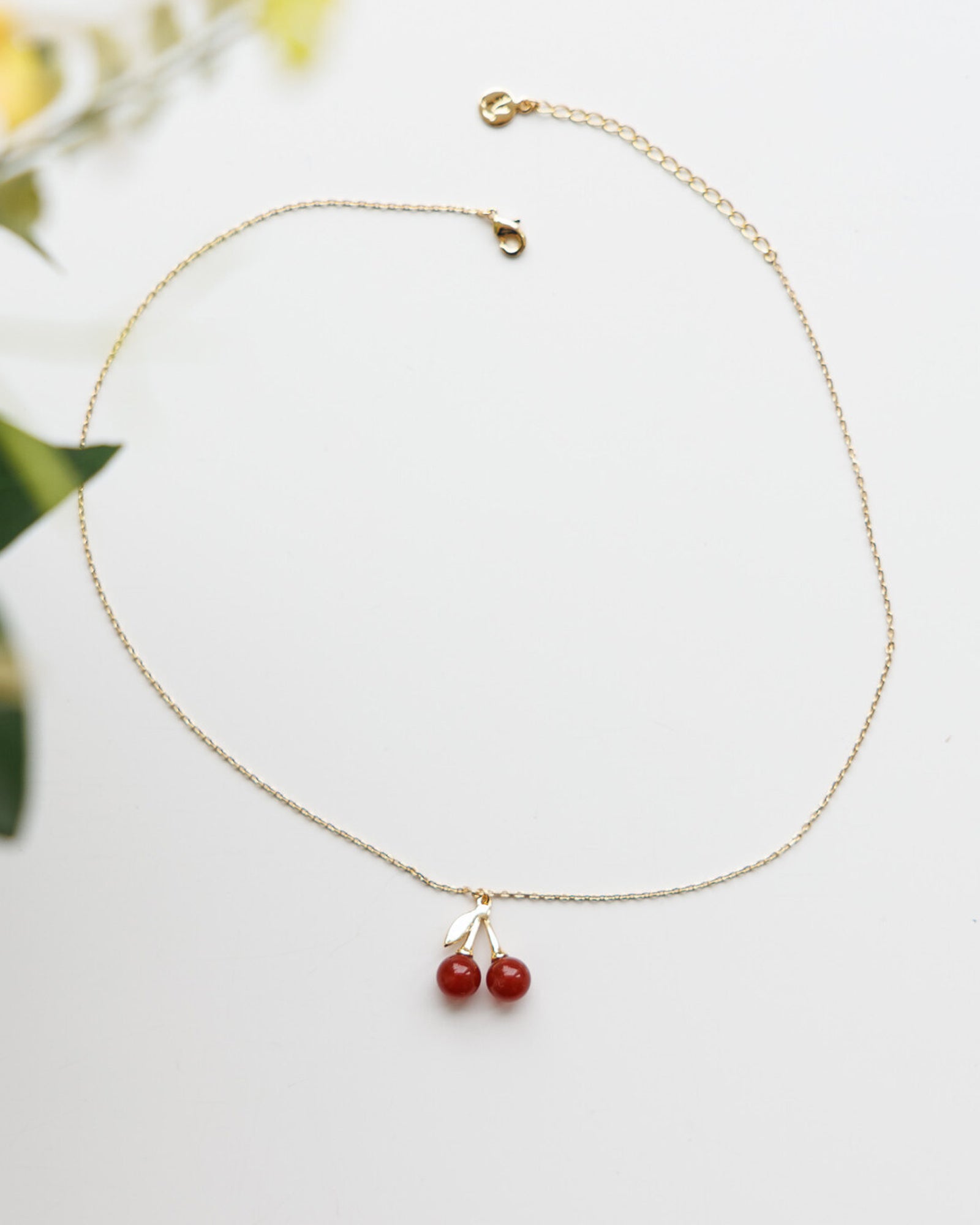 Gold necklace with red beads on a light background