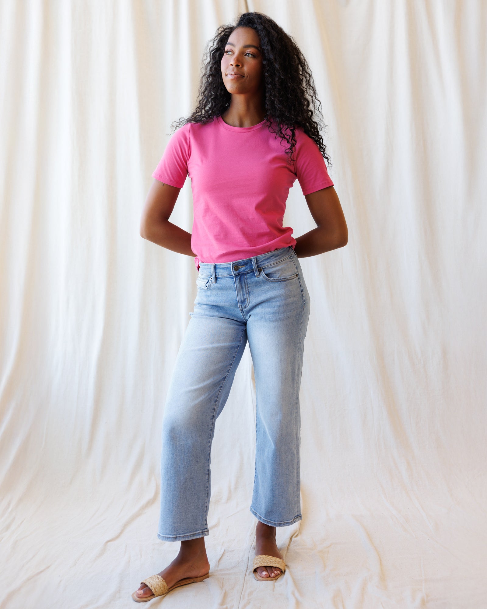 Person wearing a pink t-shirt and light blue jeans against a white background