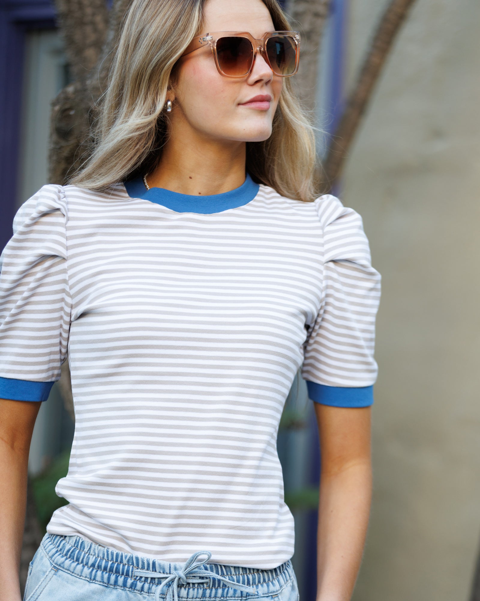 Woman wearing a striped shirt with blue accents and sunglasses.
