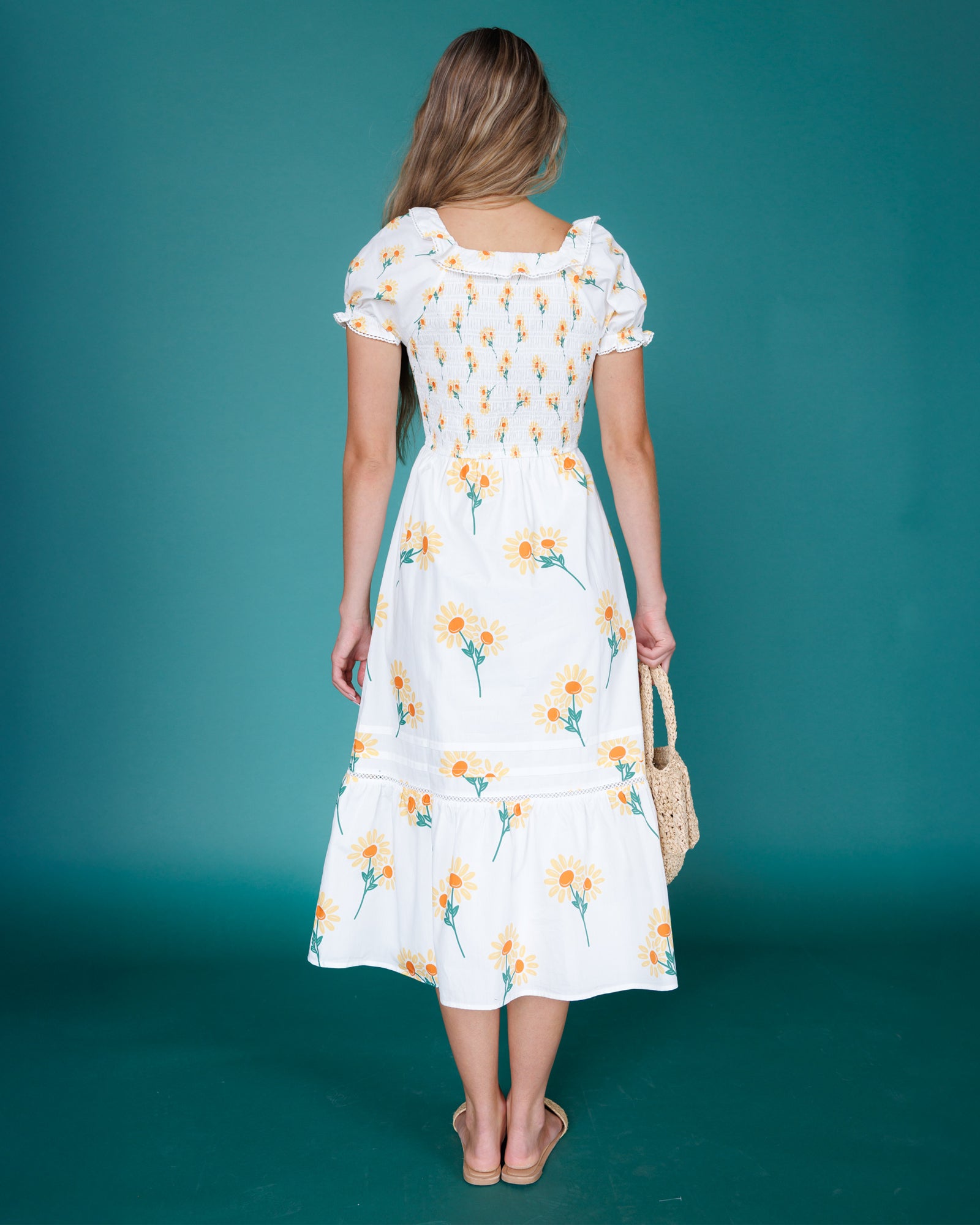 Woman wearing a white floral dress against a teal background