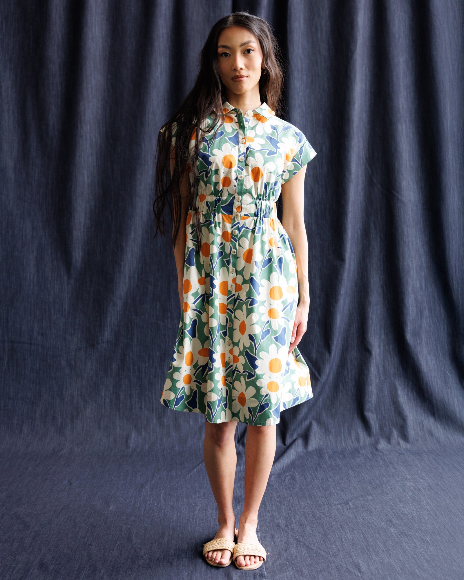 Woman wearing a floral dress against a dark blue curtain