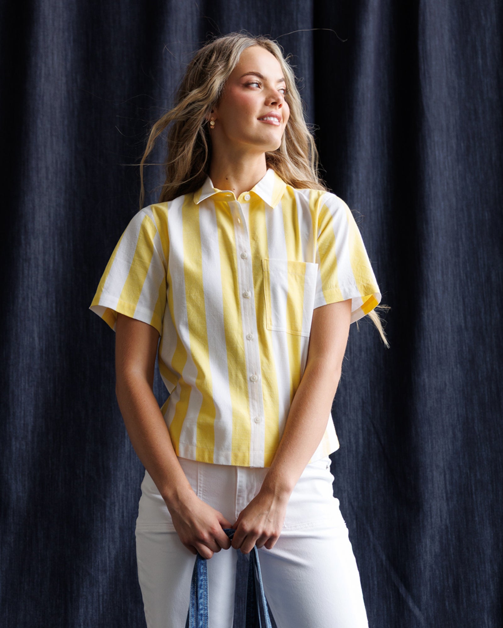 Woman wearing a yellow and white striped shirt against a dark background