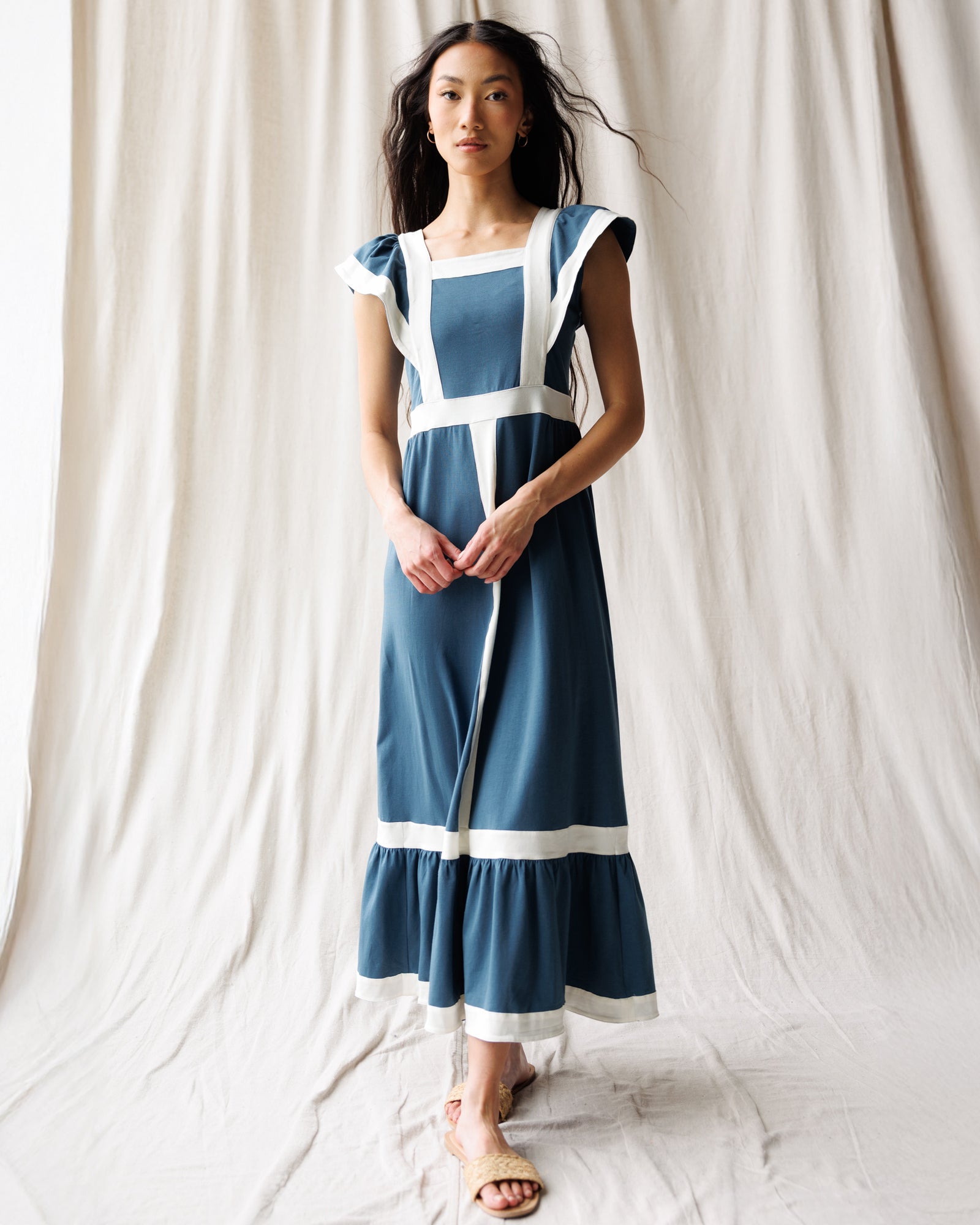 Woman wearing a blue and white dress against a plain background