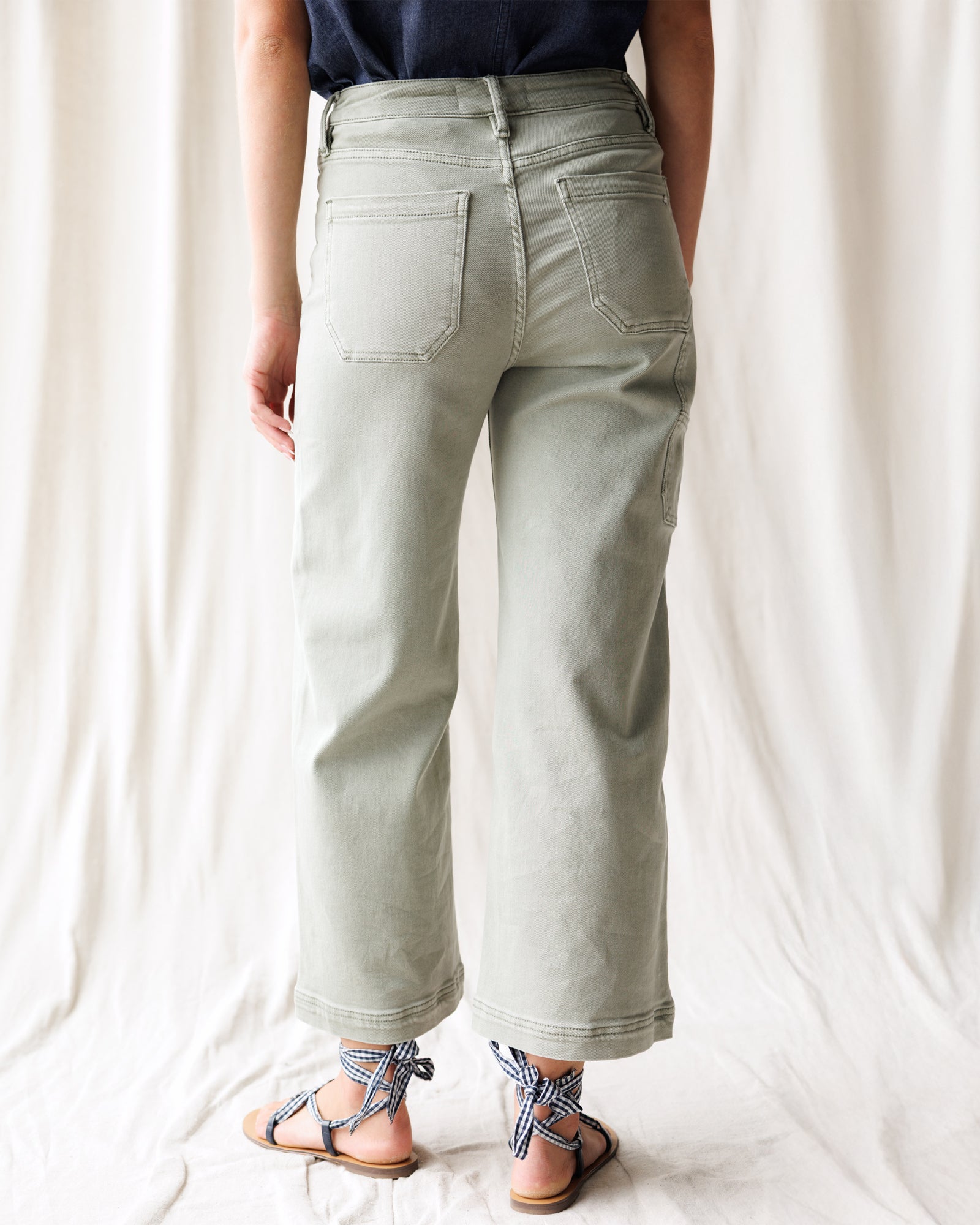 Person wearing light gray wide-leg jeans on a white background