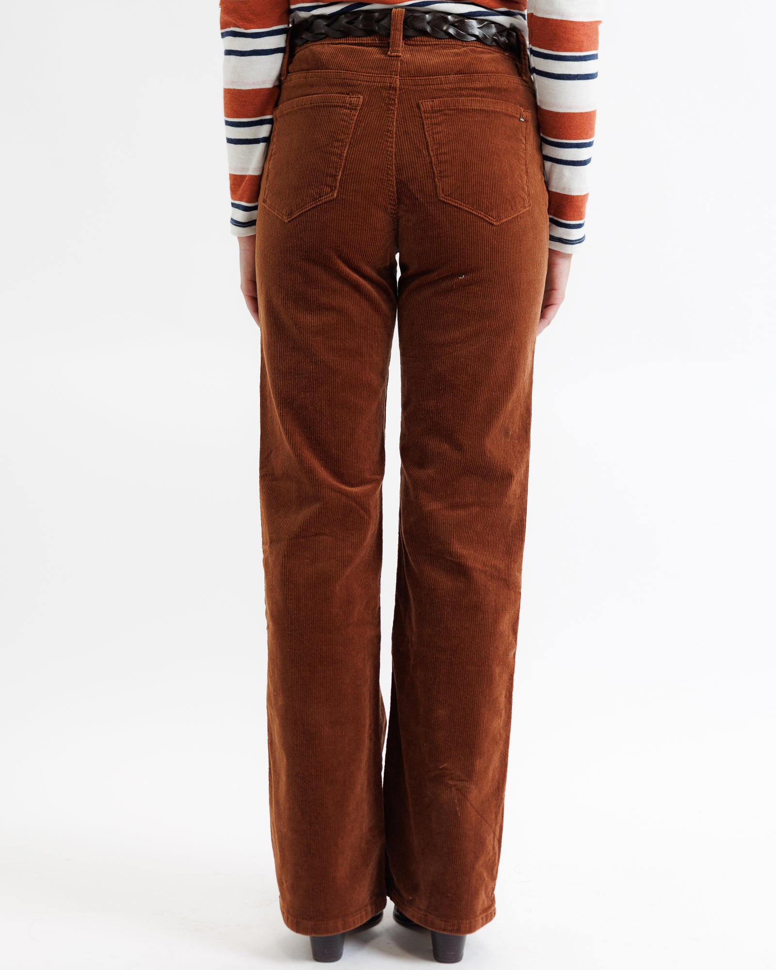 Brown corduroy pants worn by a person on a white background