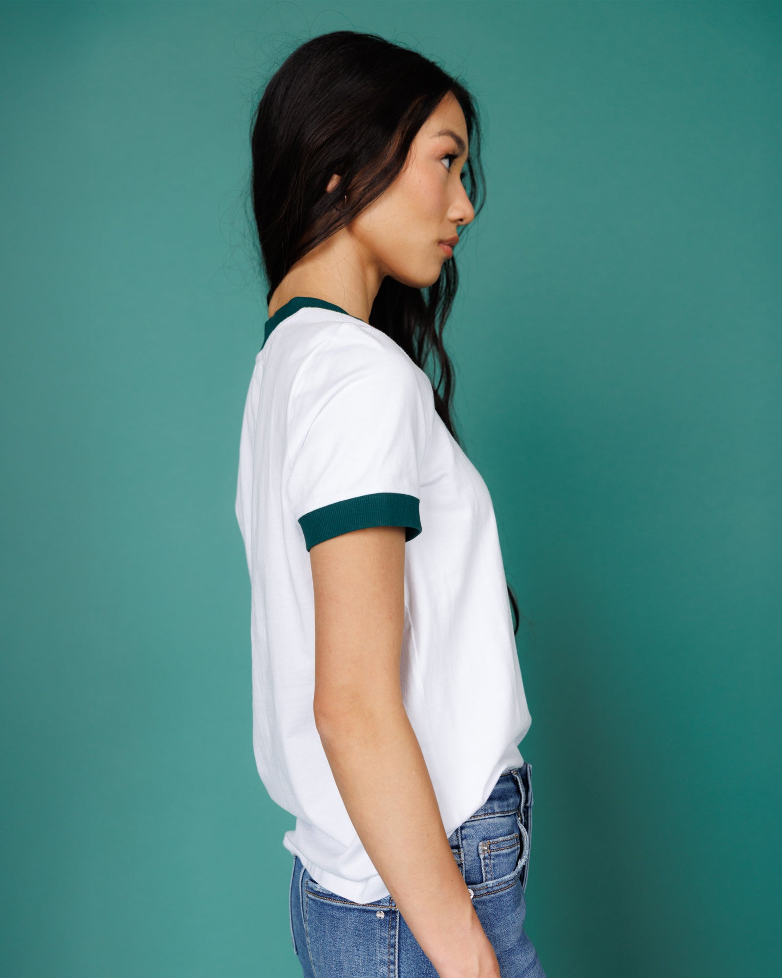 Woman wearing a white t-shirt with green accents against a teal background