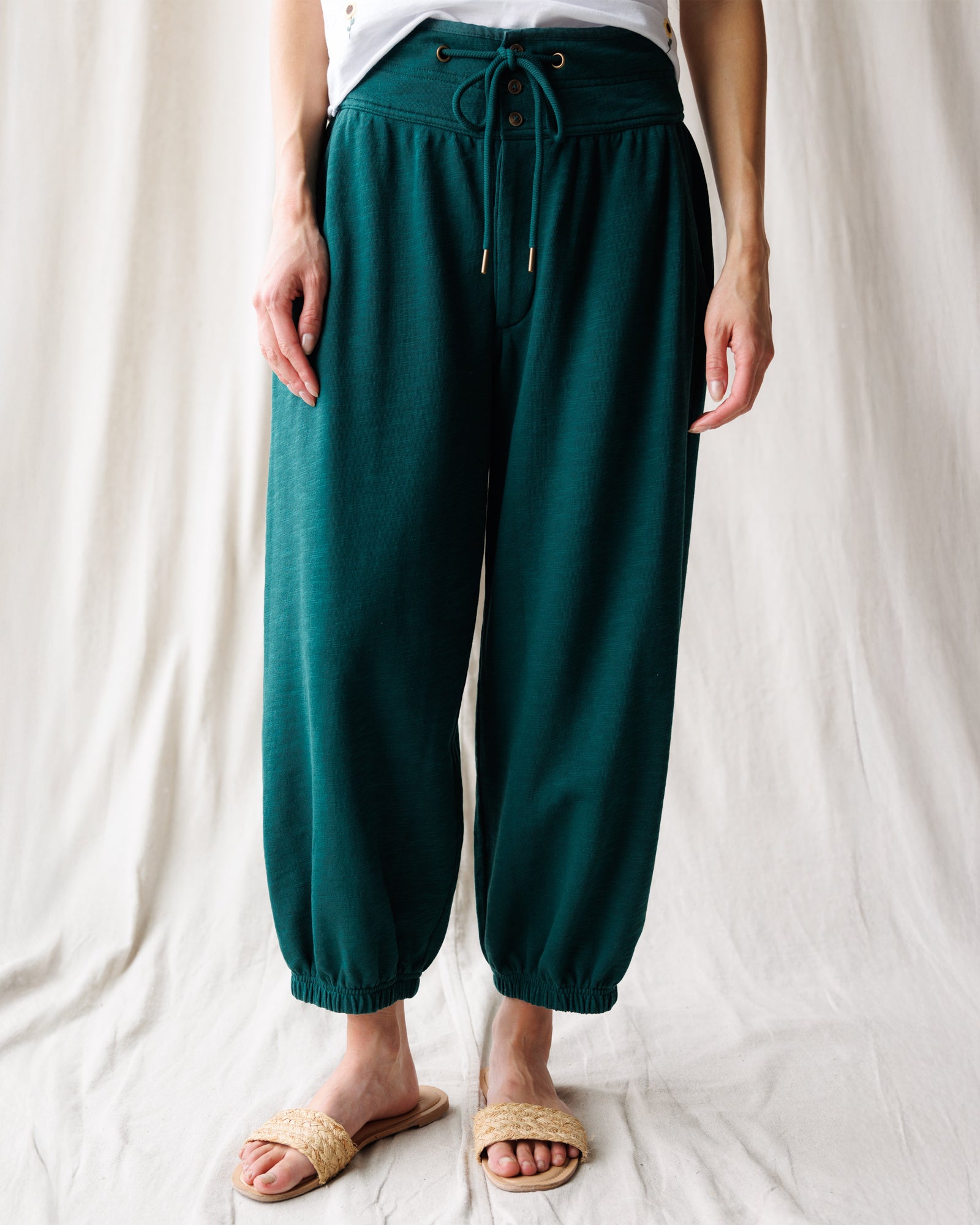 Person wearing teal pants with a drawstring waist on a white background