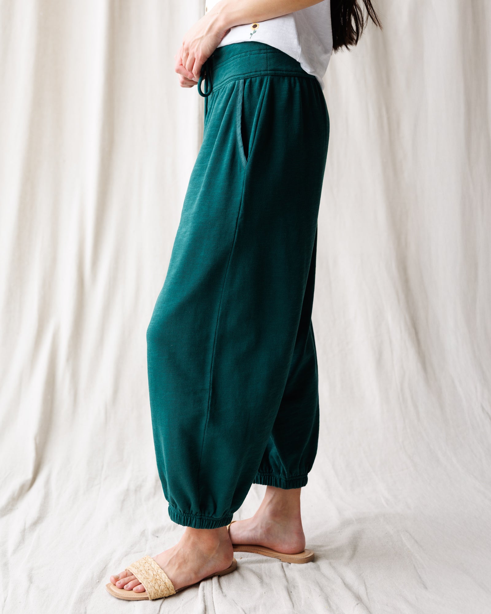Person wearing teal pants with a white background