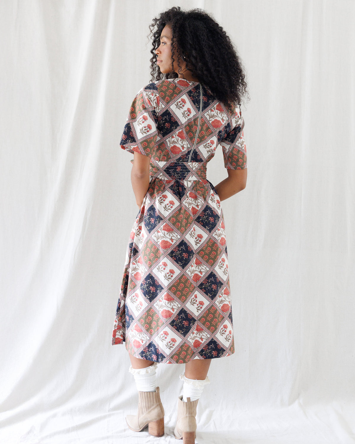 Back view of the floral patchwork midi dress highlighting the smocked elastic back waistband, hidden back zipper closure, and full coverage A-line skirt.