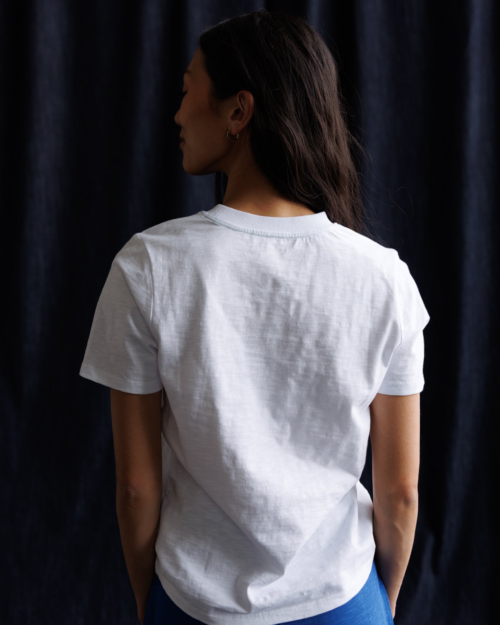 Person wearing a white t-shirt against a dark background