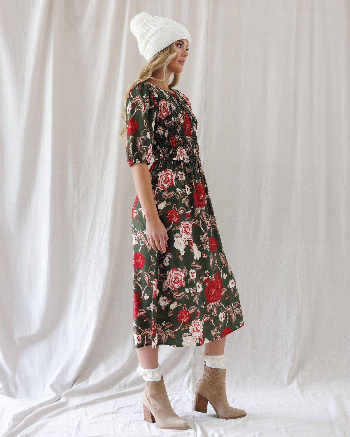 Side profile showing the fitted smocked torso, elasticized puff sleeve cuffs, and midi-length drape of the floral A-line dress.