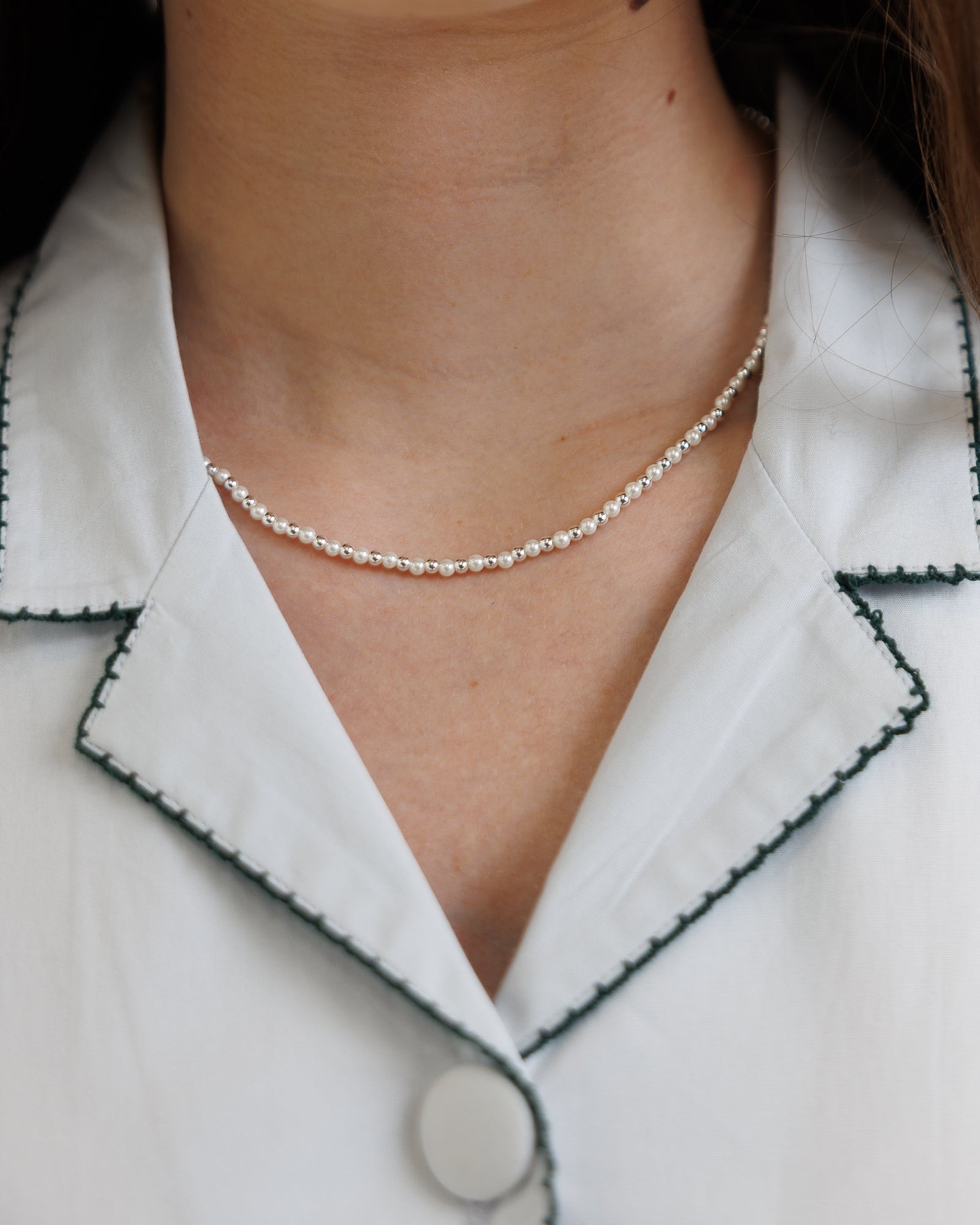 Necklace worn by a person with a white shirt and green trim