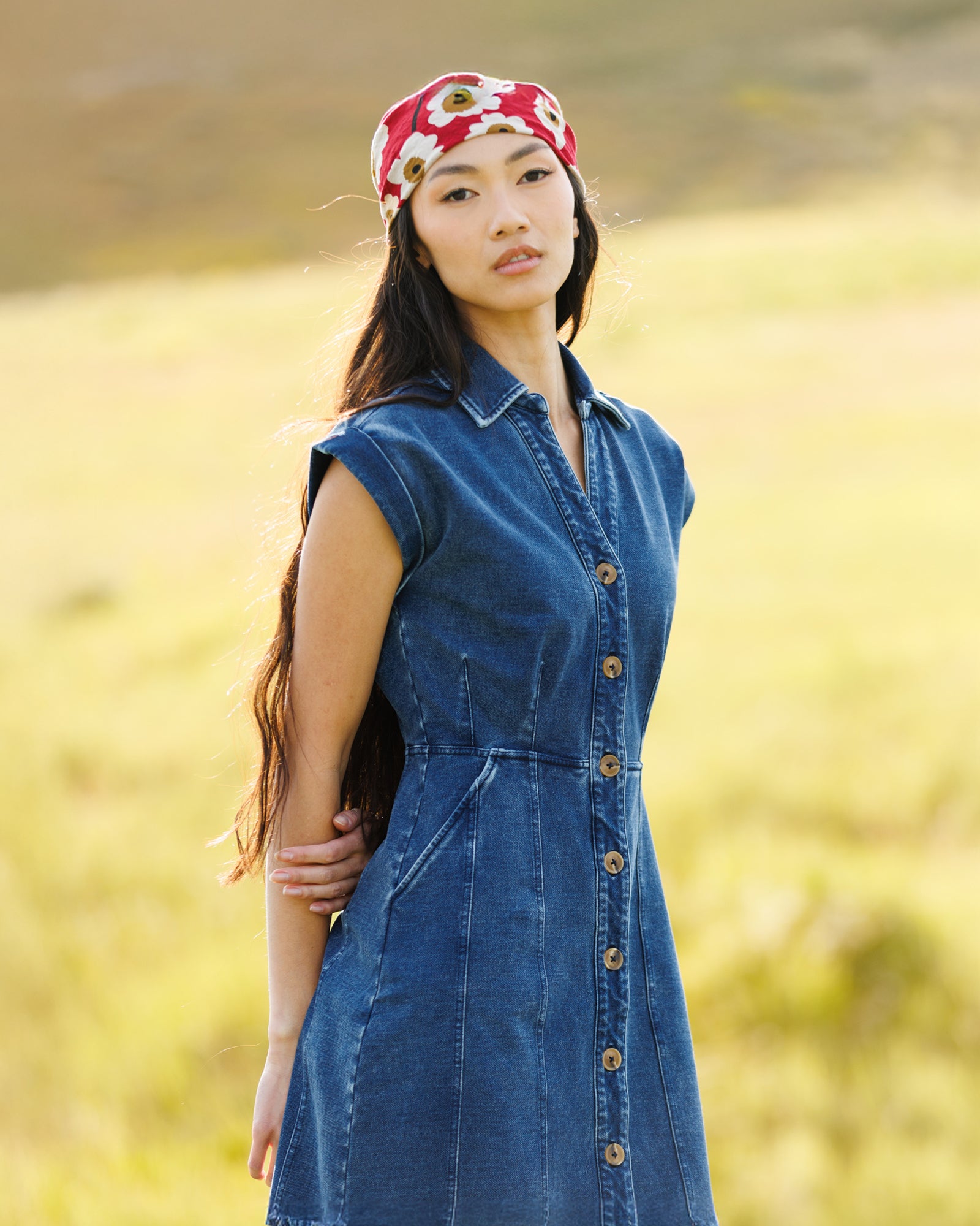 Image of woman wearing a dark denim knee-length dress in a field