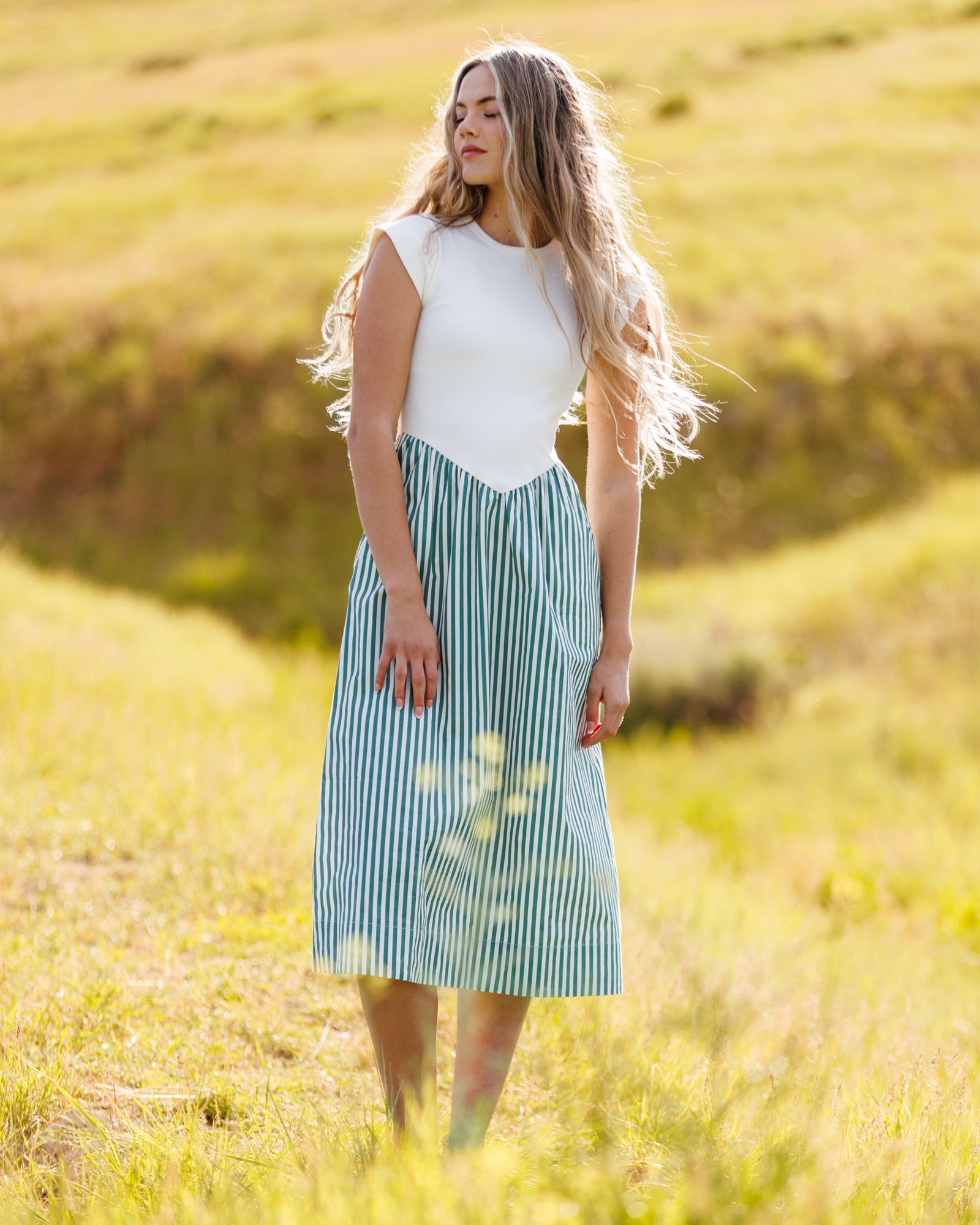 Woman wearing a white and green striped dress standing in a field