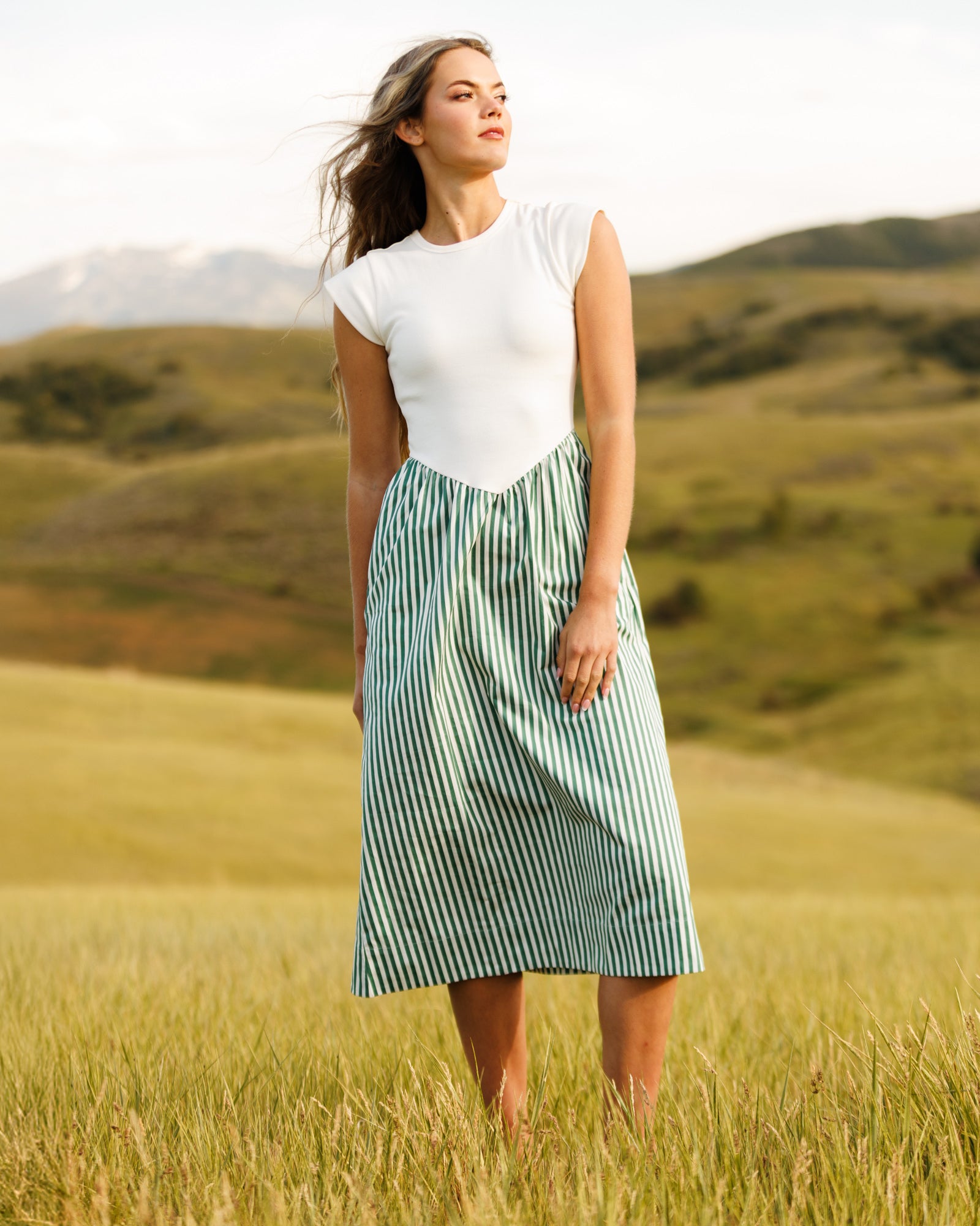Woman wearing a white and green striped dress standing in a field