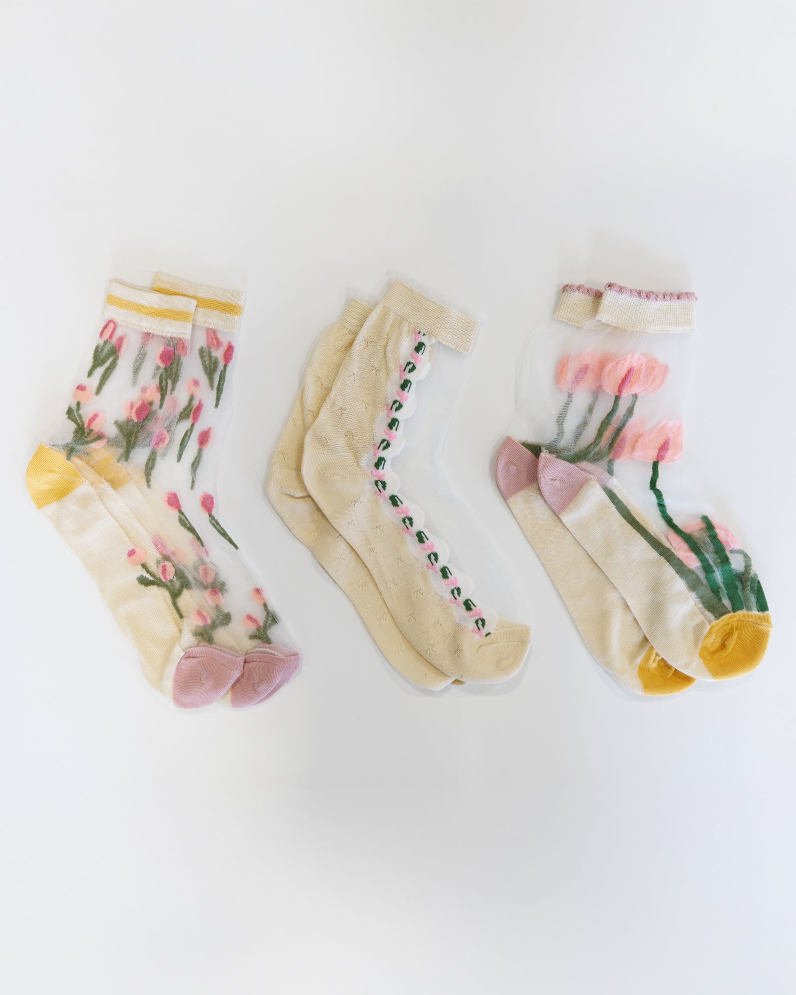Three pairs of socks with floral designs on a white background