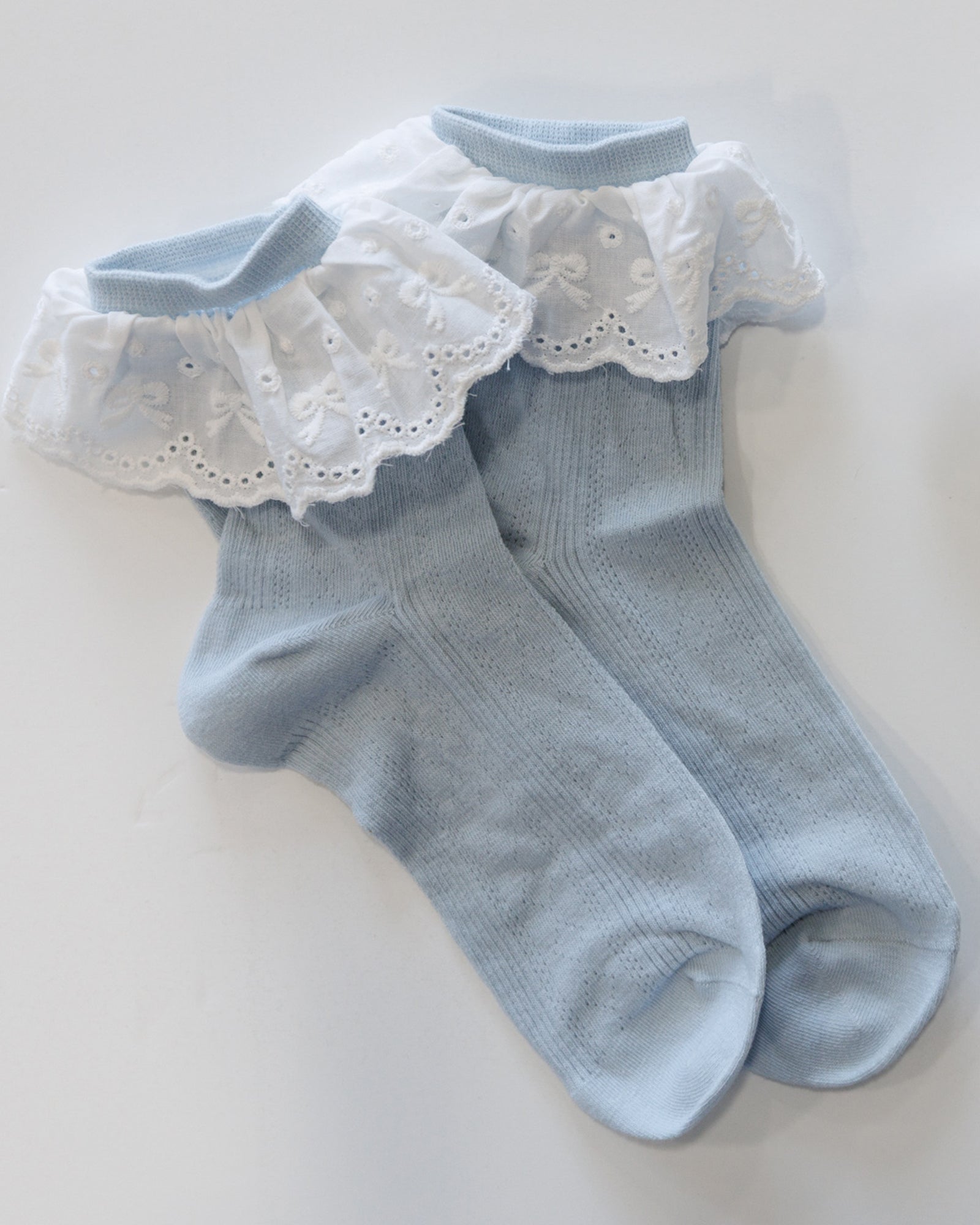 Light blue socks with white lace trim on a light background