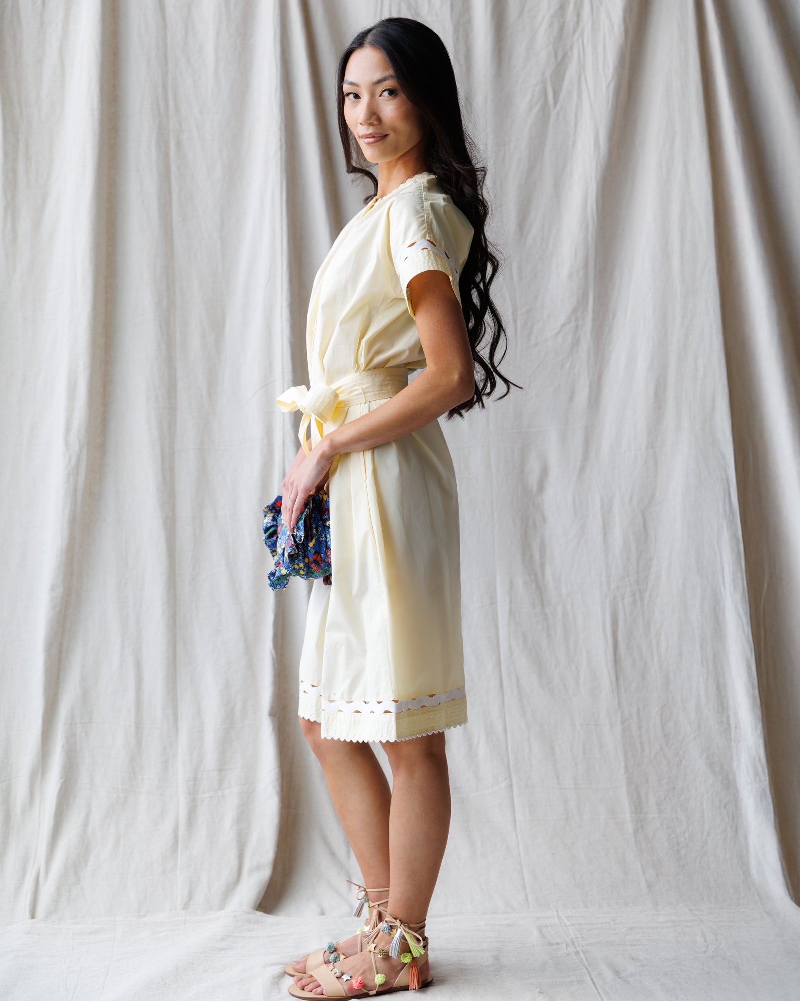 Woman in a light-colored dress standing against a plain background
