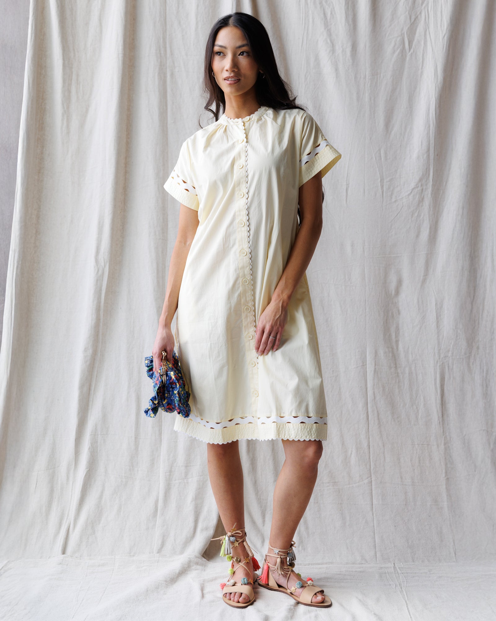 Woman wearing a white dress with lace details against a plain background