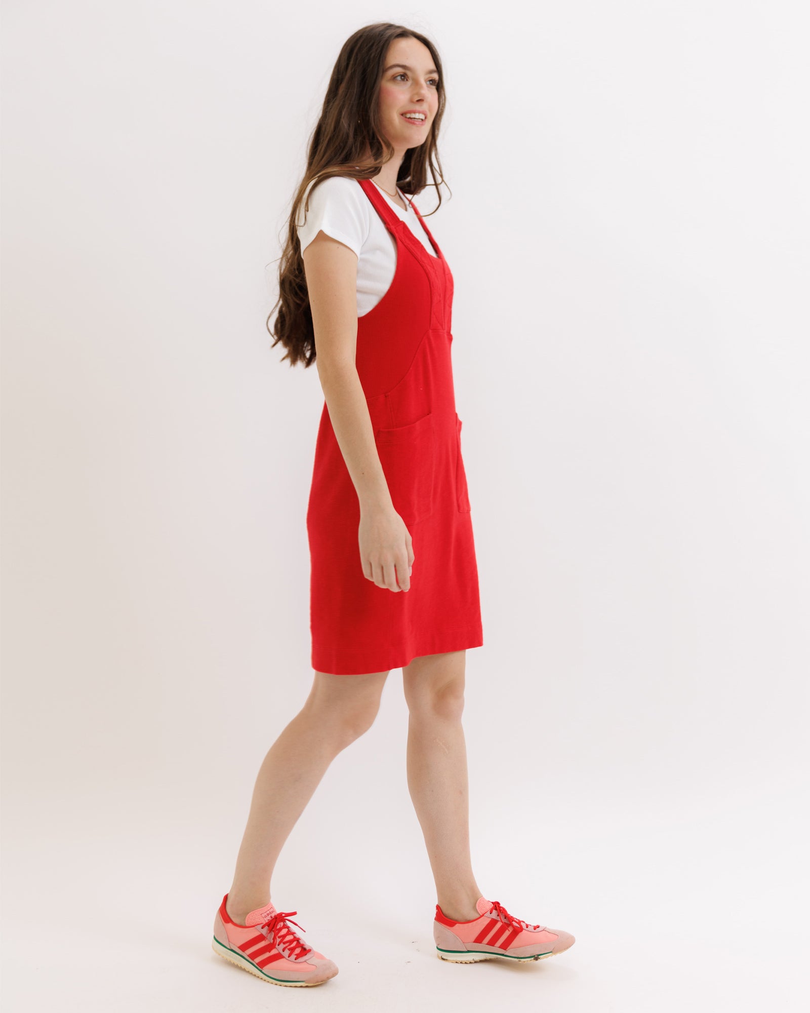 Woman wearing a red dress with a white top underneath on a plain background