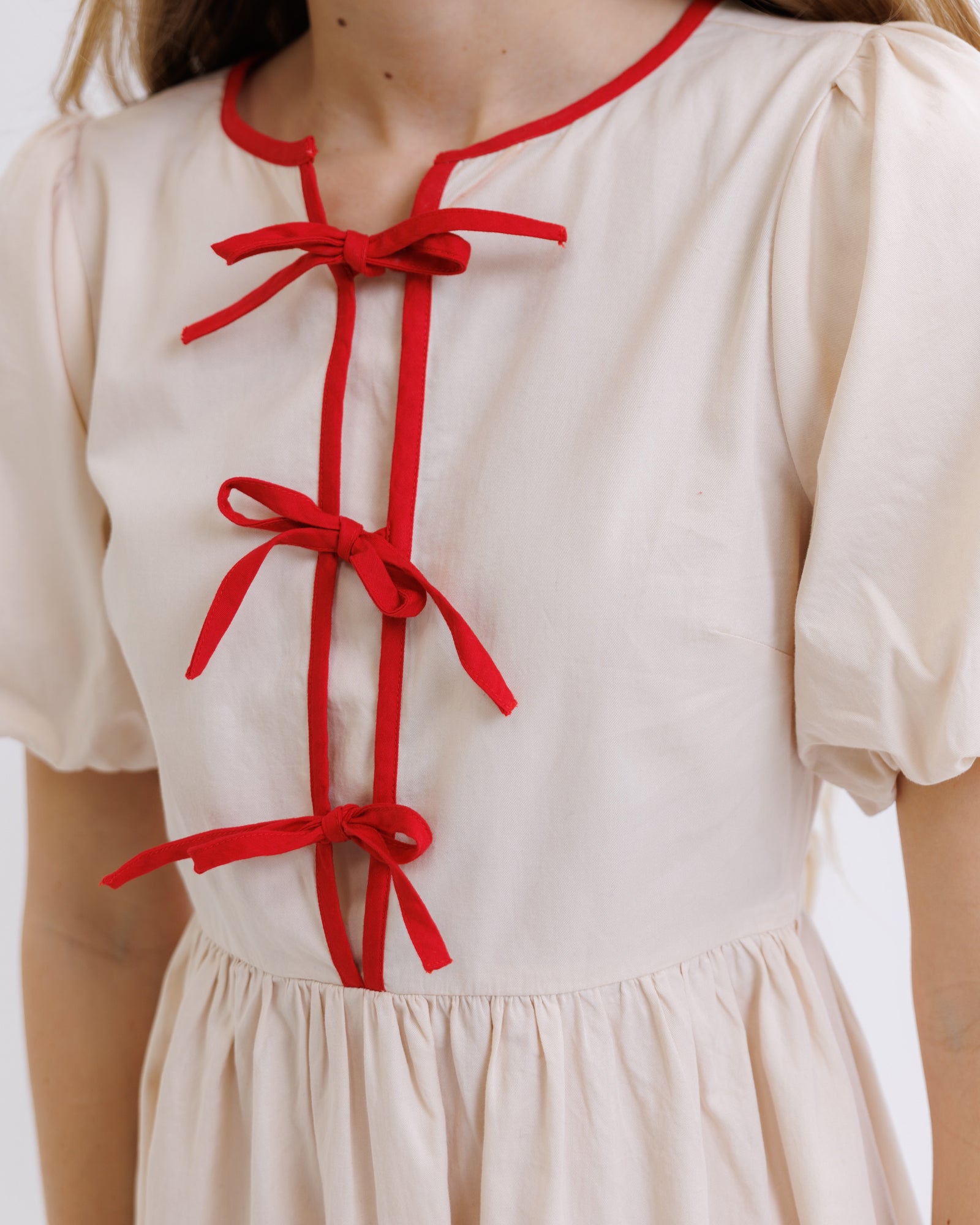 Beige dress with red bows on a plain background