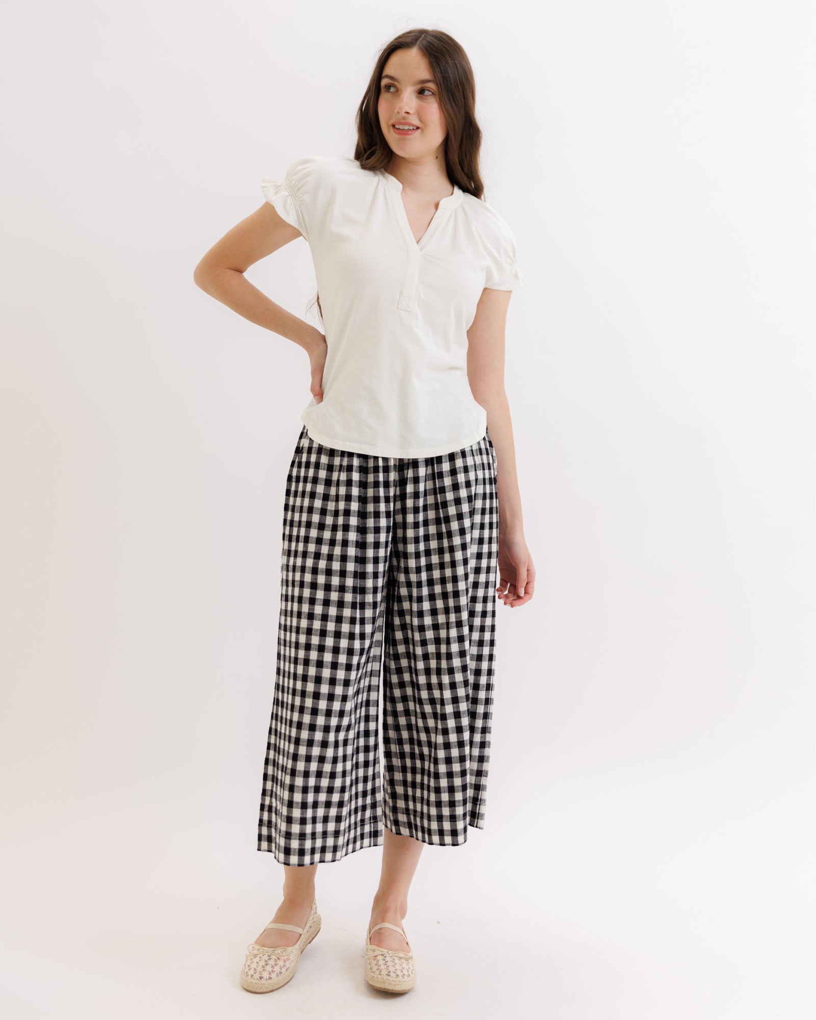 Woman wearing a white blouse and black checkered pants on a white background