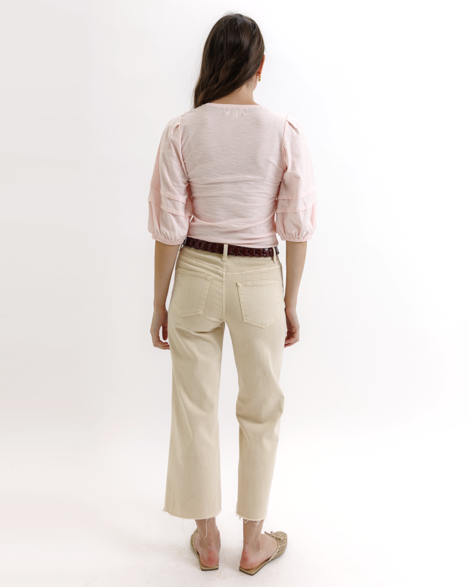 Woman wearing a light pink top and beige pants on a white background