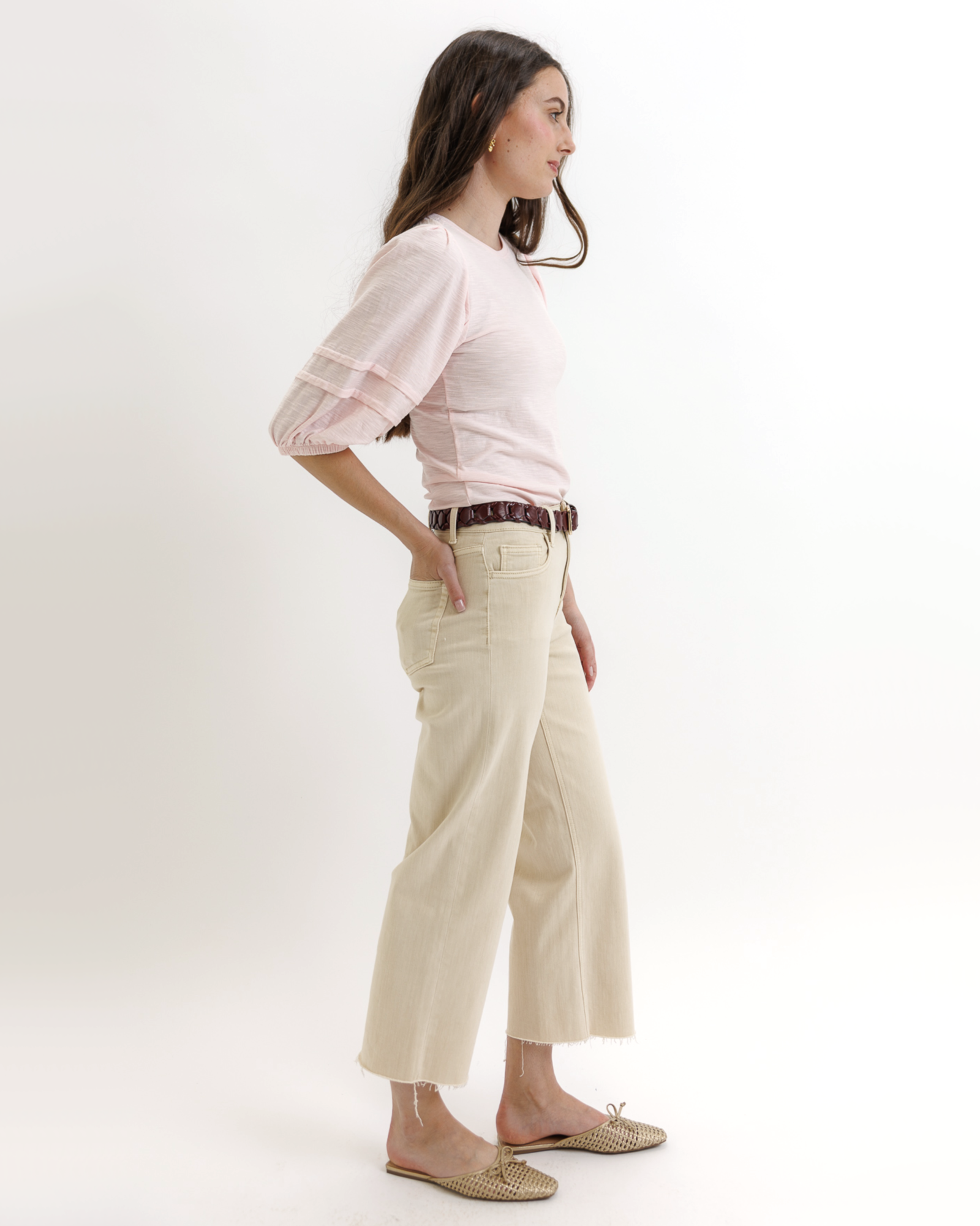Woman wearing a light pink top and beige pants on a white background