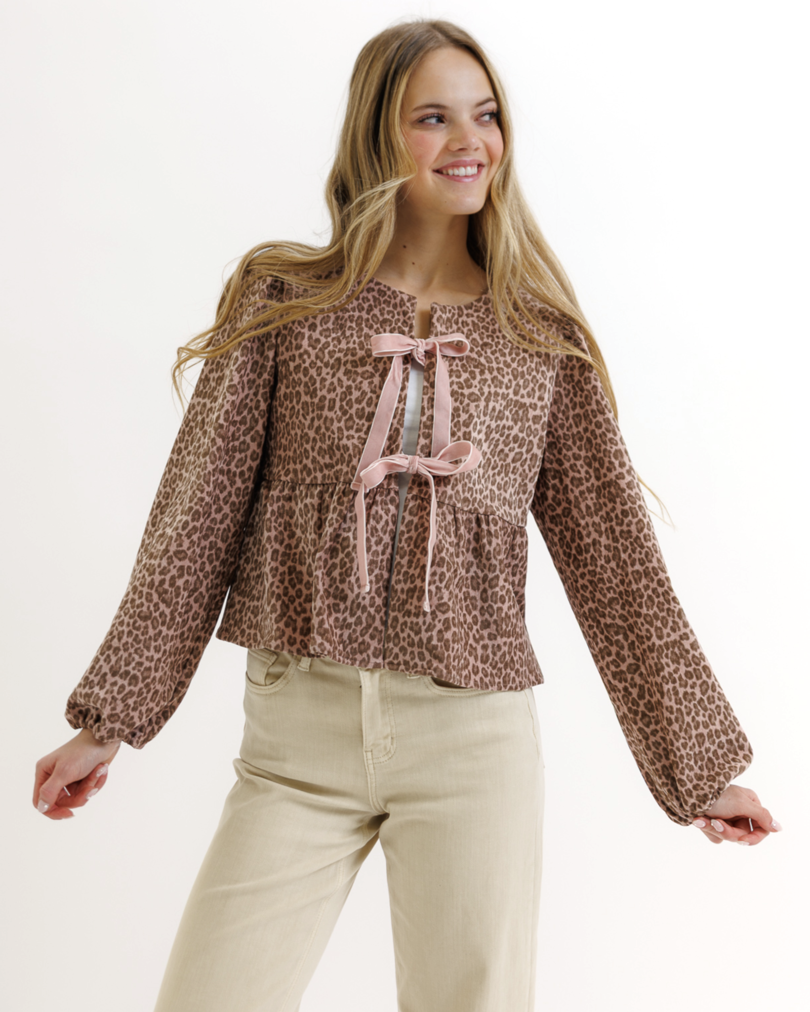 Woman wearing a leopard print blouse with pink bow ties on a white background
