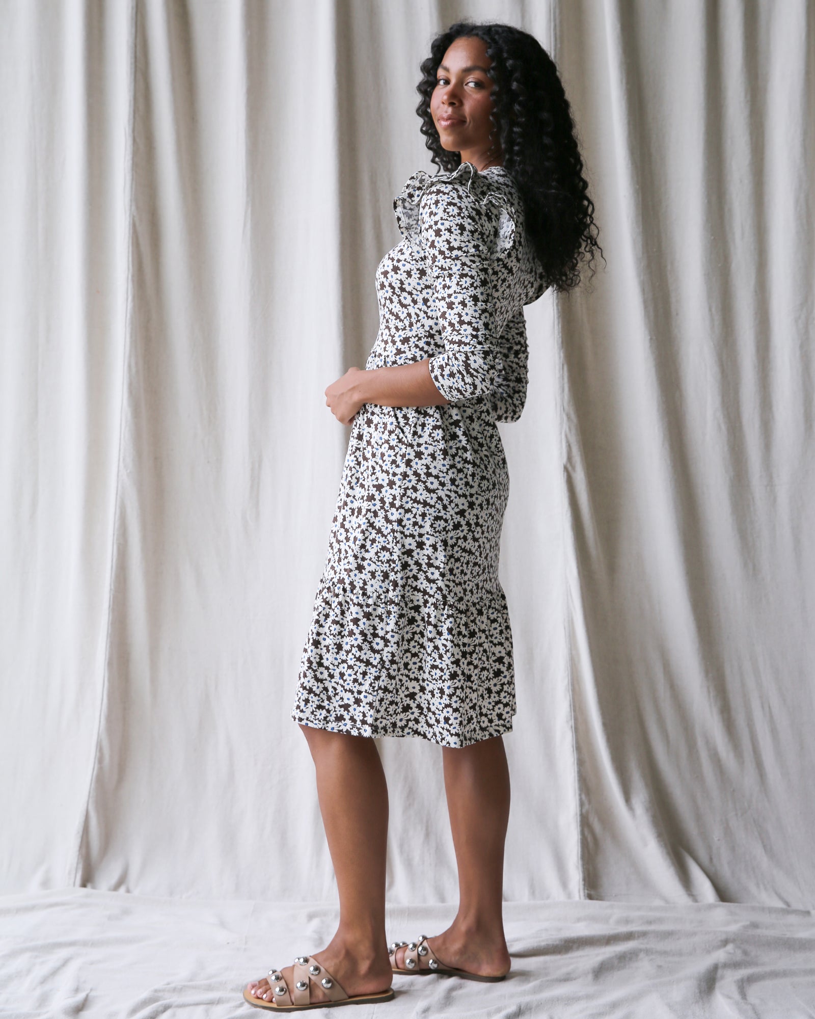 Woman wearing a black and white patterned dress standing against a plain background