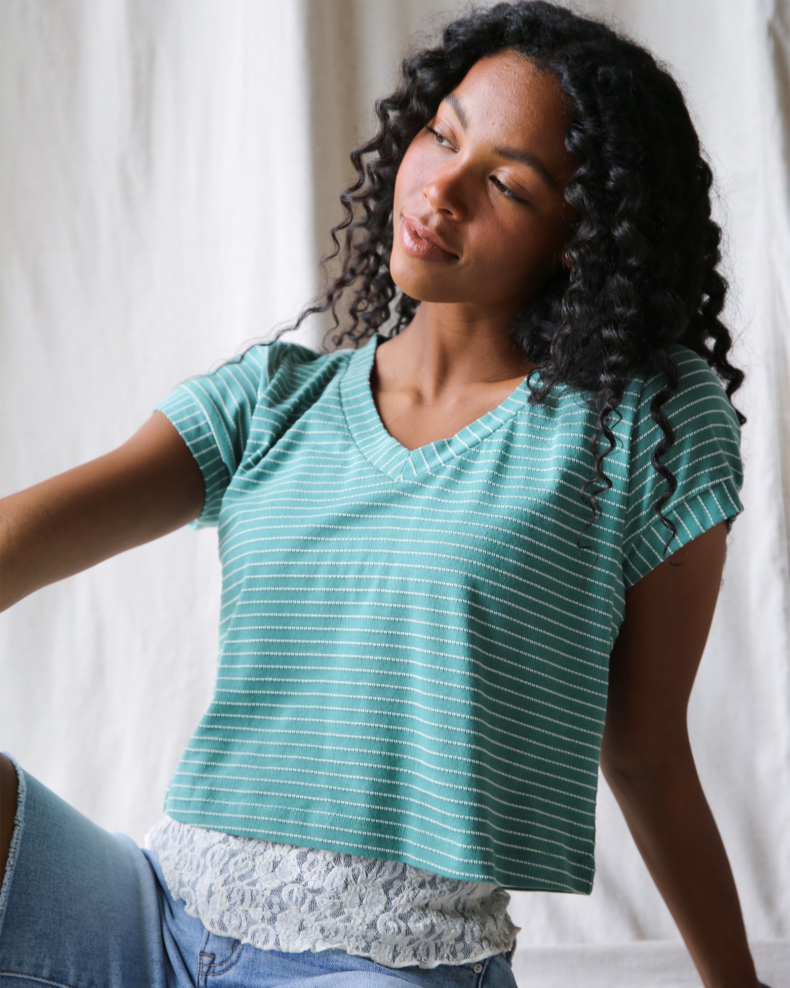 Woman wearing a teal striped shirt against a white background
