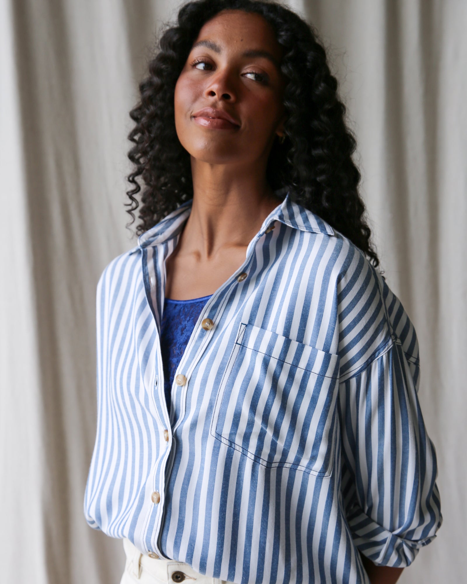Woman wearing a blue and white striped shirt against a neutral background