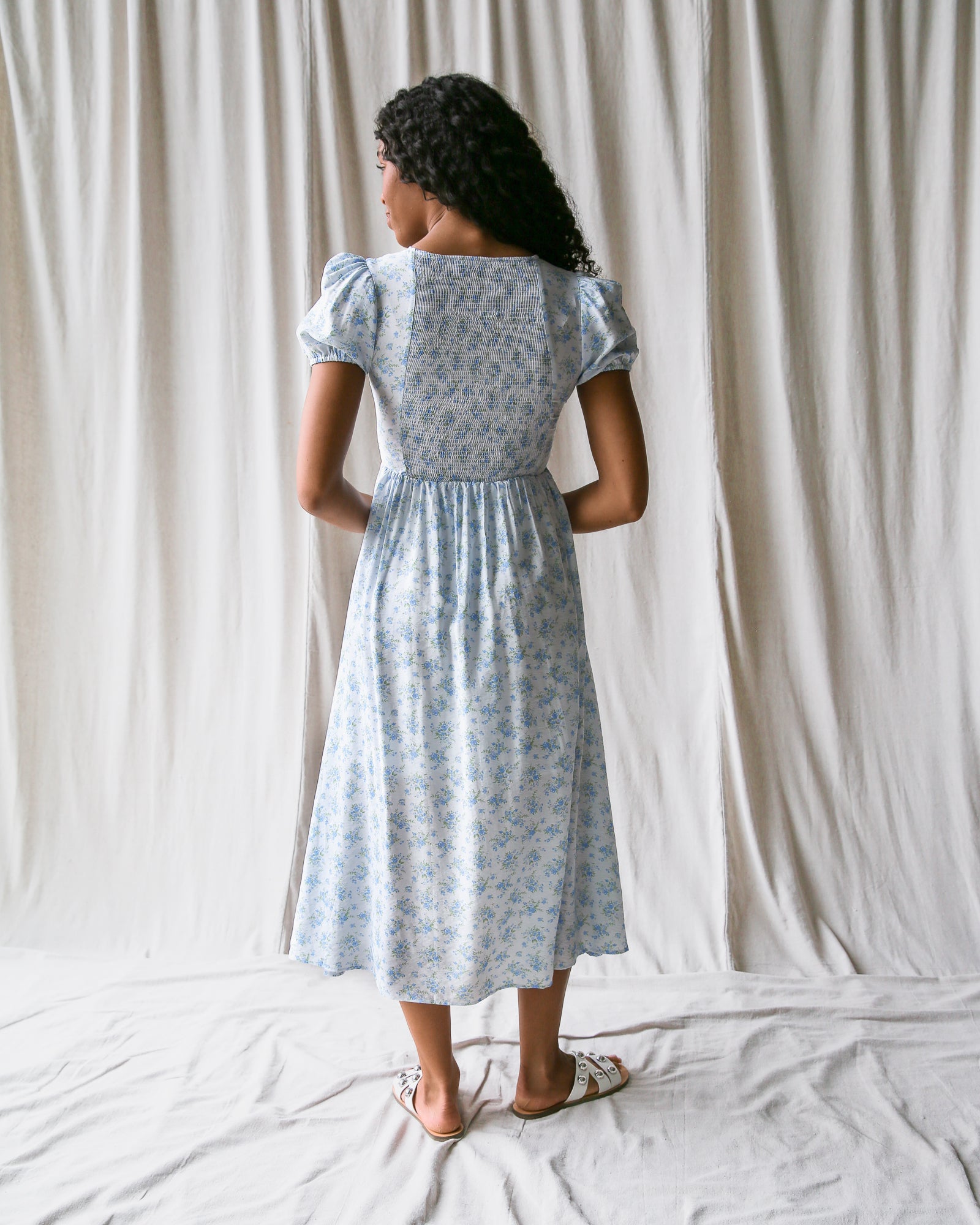 Woman wearing a light blue floral dress against a plain white background