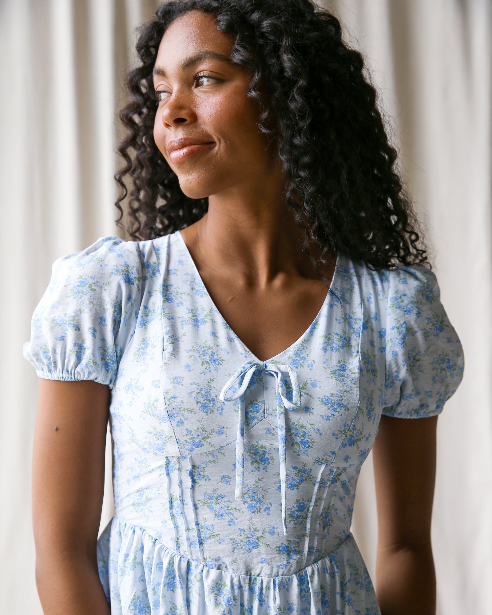 Woman wearing a light blue floral dress against a neutral background