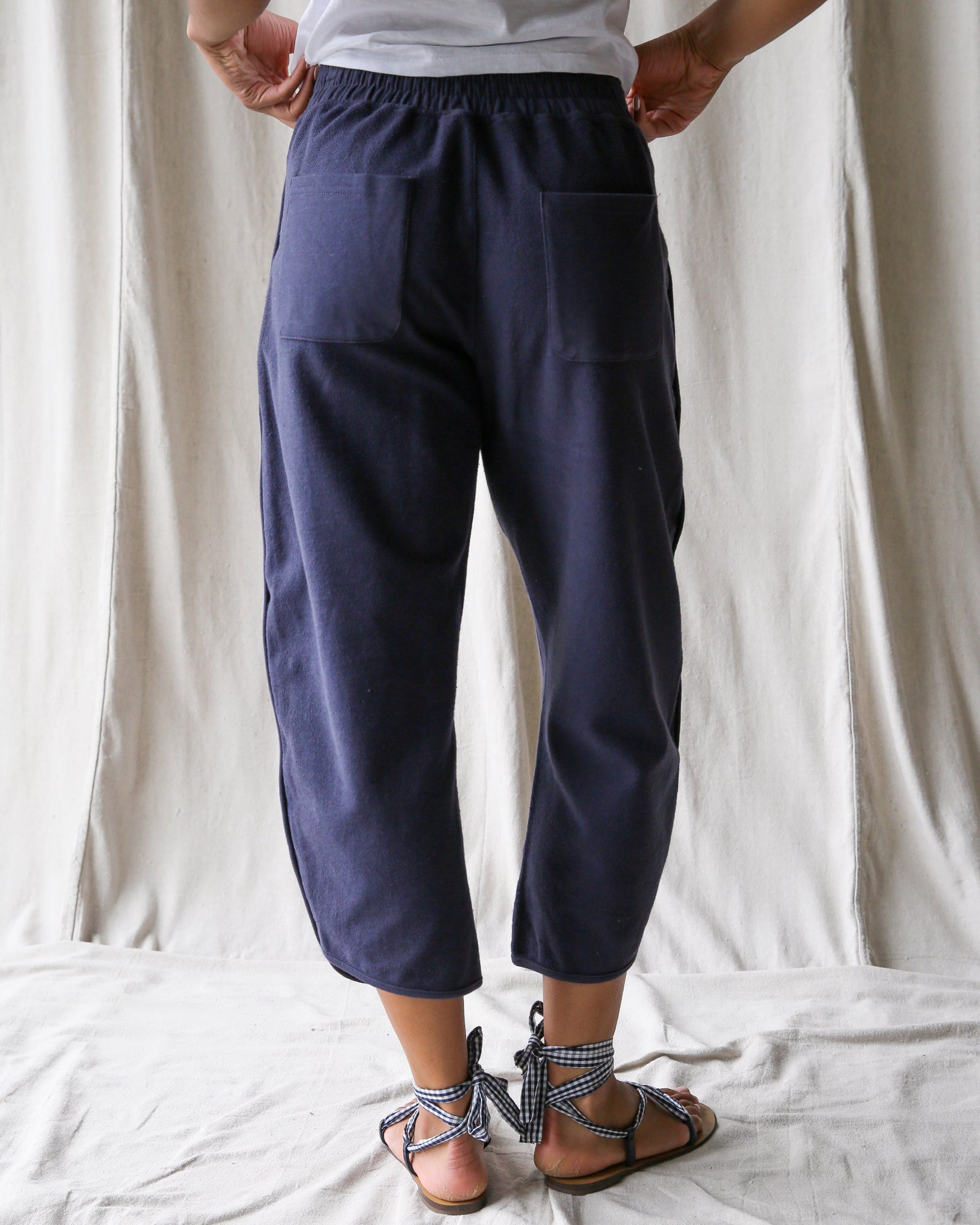 Person wearing navy blue pants with a white background