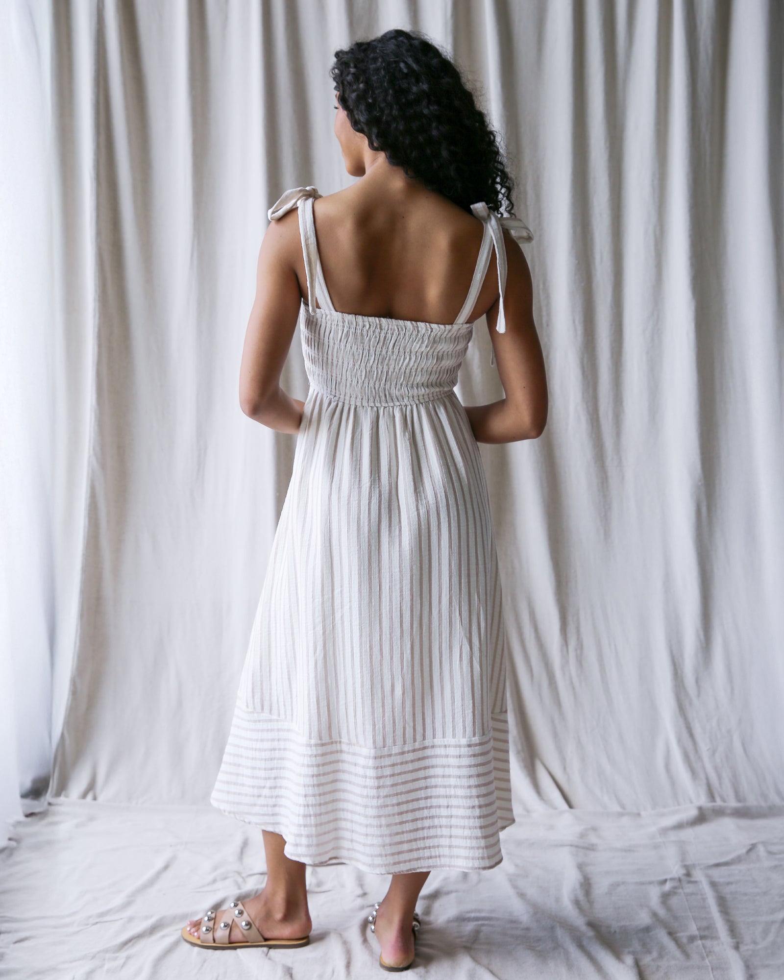 Woman in a white dress against a white curtain background